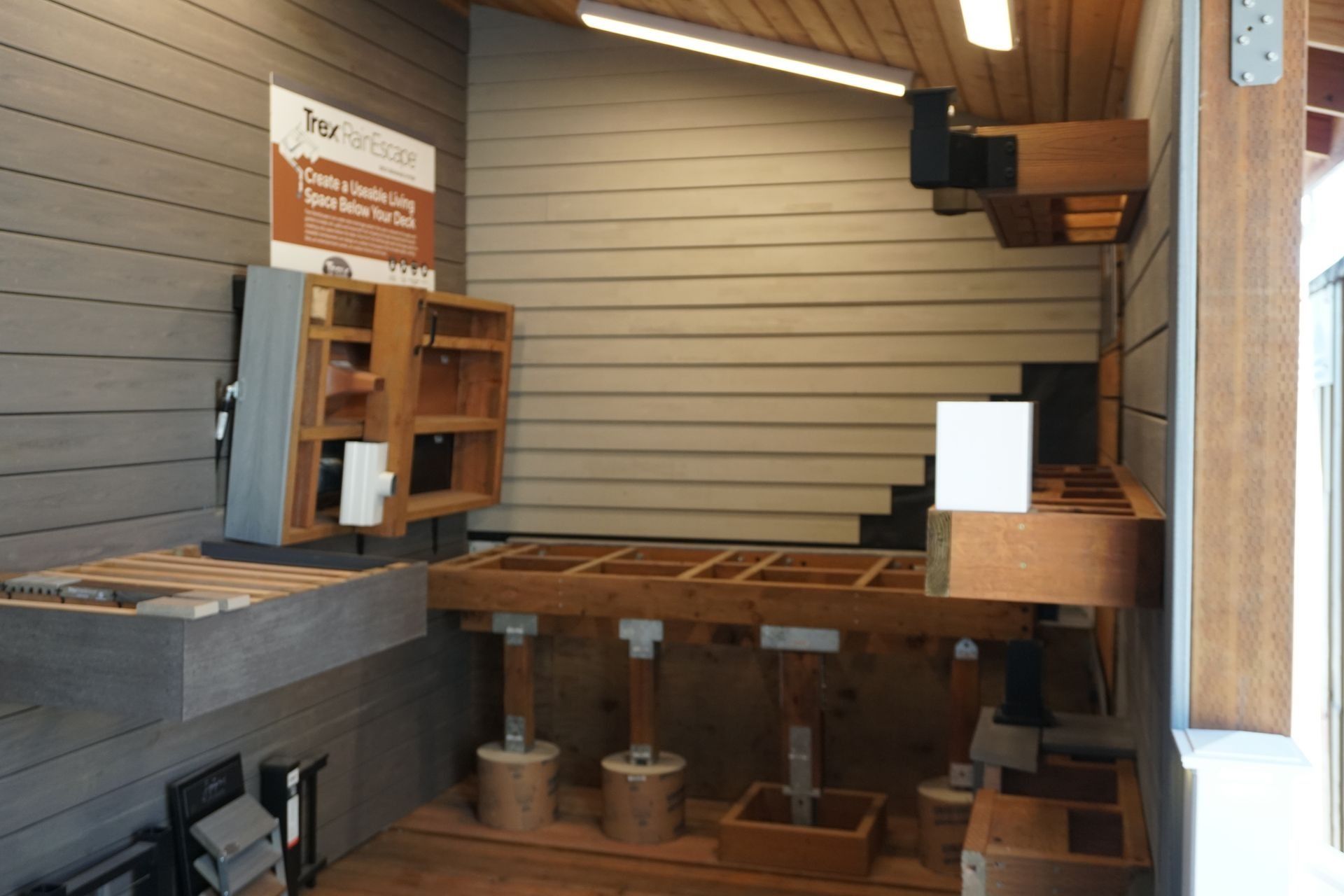 Interior display showcasing cabinetry and building materials. Wooden frameworks and mounted elements against gray walls.