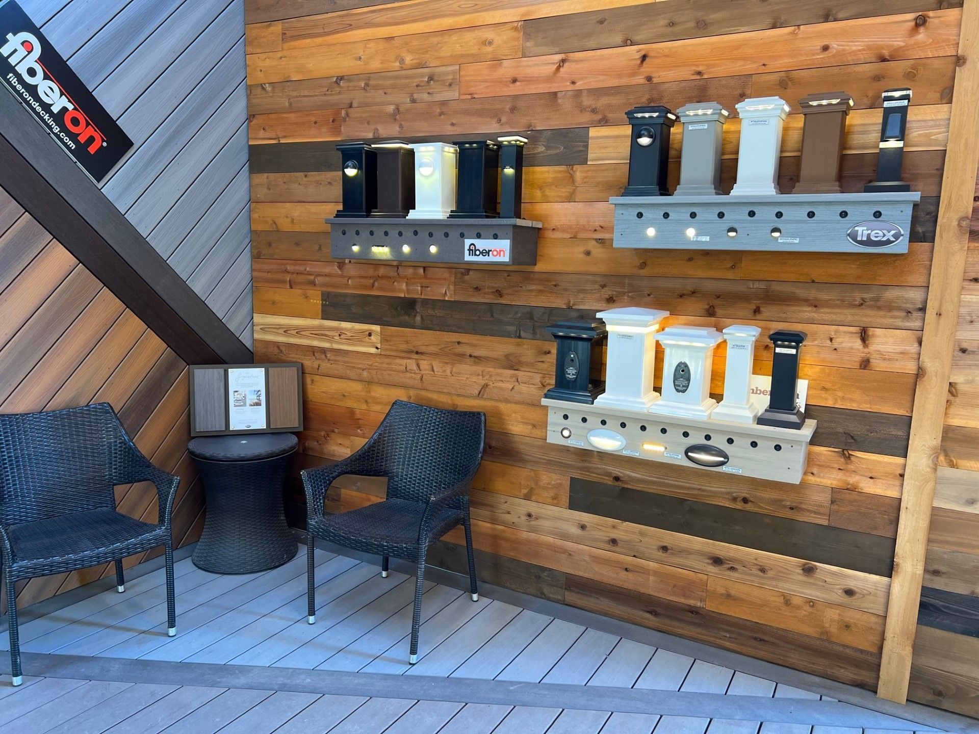 Display of Fiberon deck post lights against wood wall, with seating in foreground.