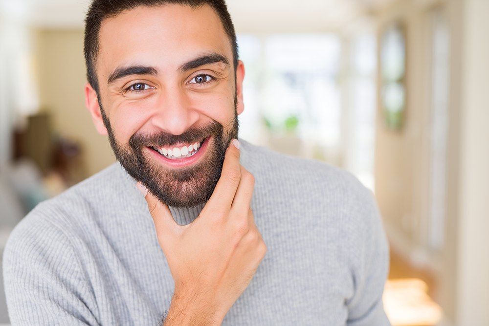 guy smiling inside house with hand on chin happy