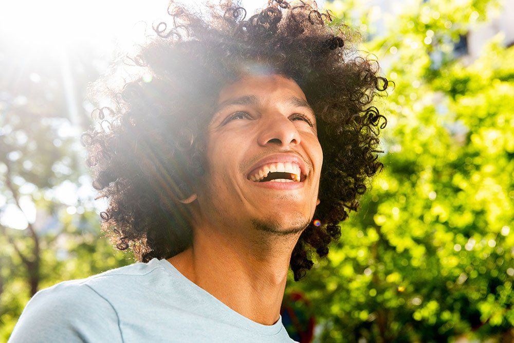 guy standing outside in the sun smiling and happy