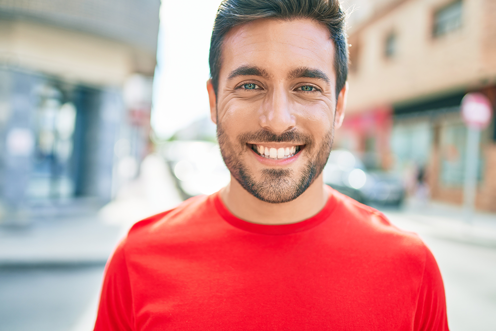 guy standing outside subtly smiling showing his teeth
