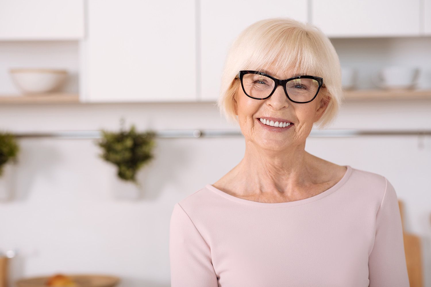 older lady standing in a kitchen smiling at the camera