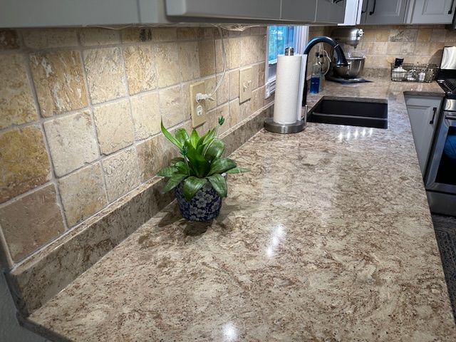 Kitchen countertop with plant, paper towel holder, sink, and backsplash tiles. Kitchen countertop with plant, paper towel holder, sink, and backsplash tiles.