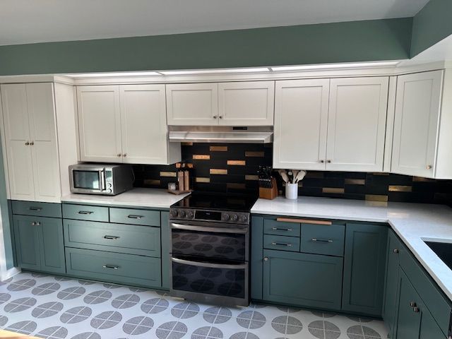 Kitchen with gray cabinets, stainless steel appliances, and multi-colored tiled floor.