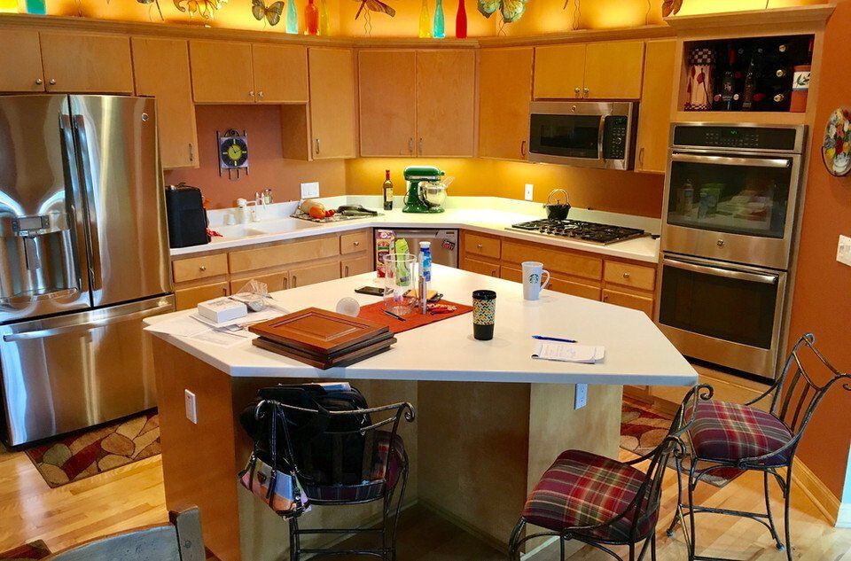 Bright kitchen with stainless steel appliances, light wood cabinets, and an island with bar stools.
