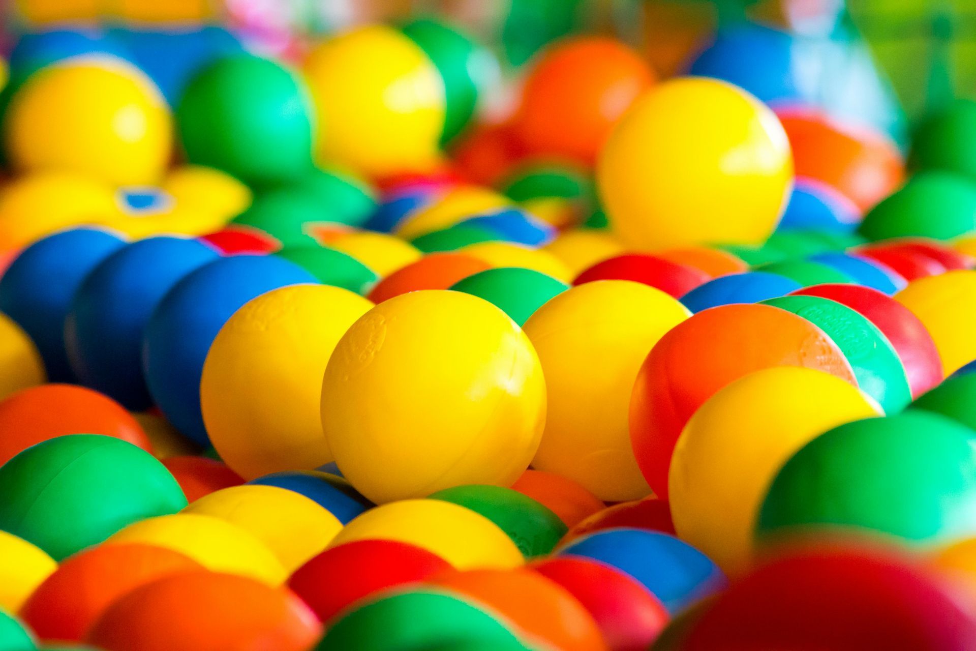 Bolas de plástico coloridas em uma piscina de bolinhas, com esferas azuis, amarelas, verdes e laranja.