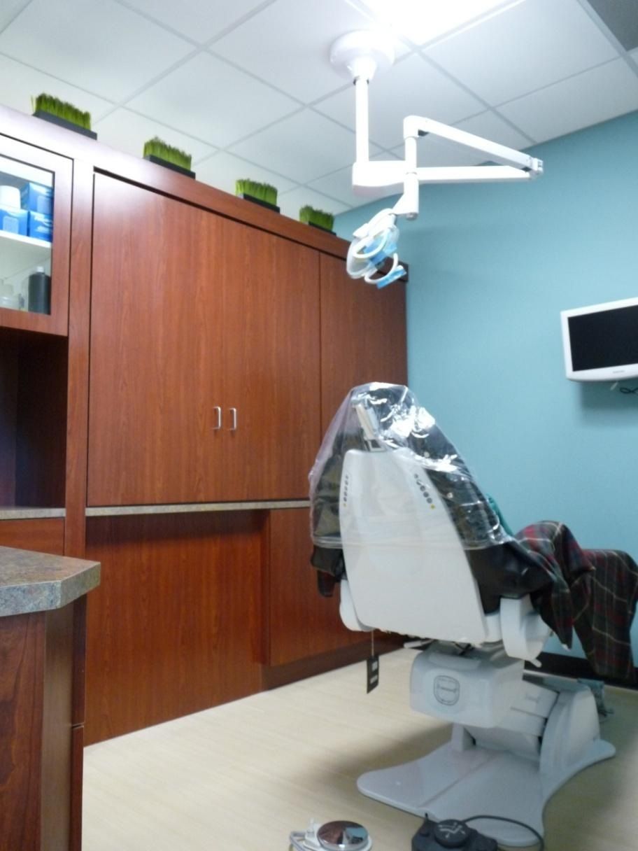 Dental exam room with chair, cabinet, medical light, and blue wall.