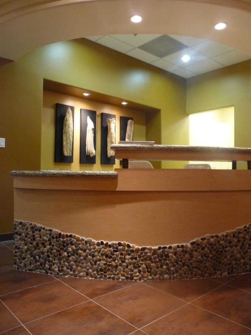 Reception desk with a stone base and artwork on an olive-green wall.