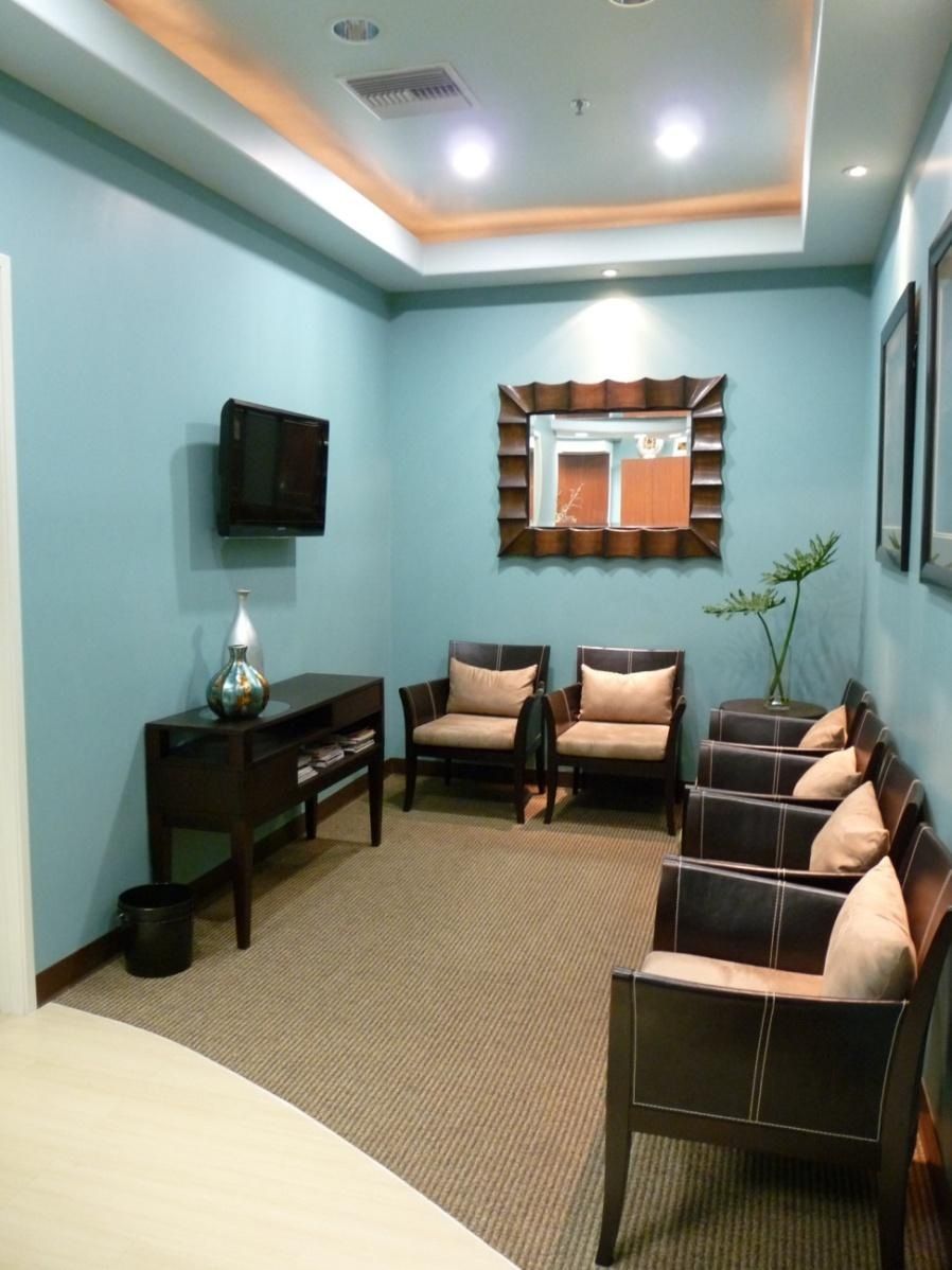 Waiting room with blue walls, brown furniture, and a small television.