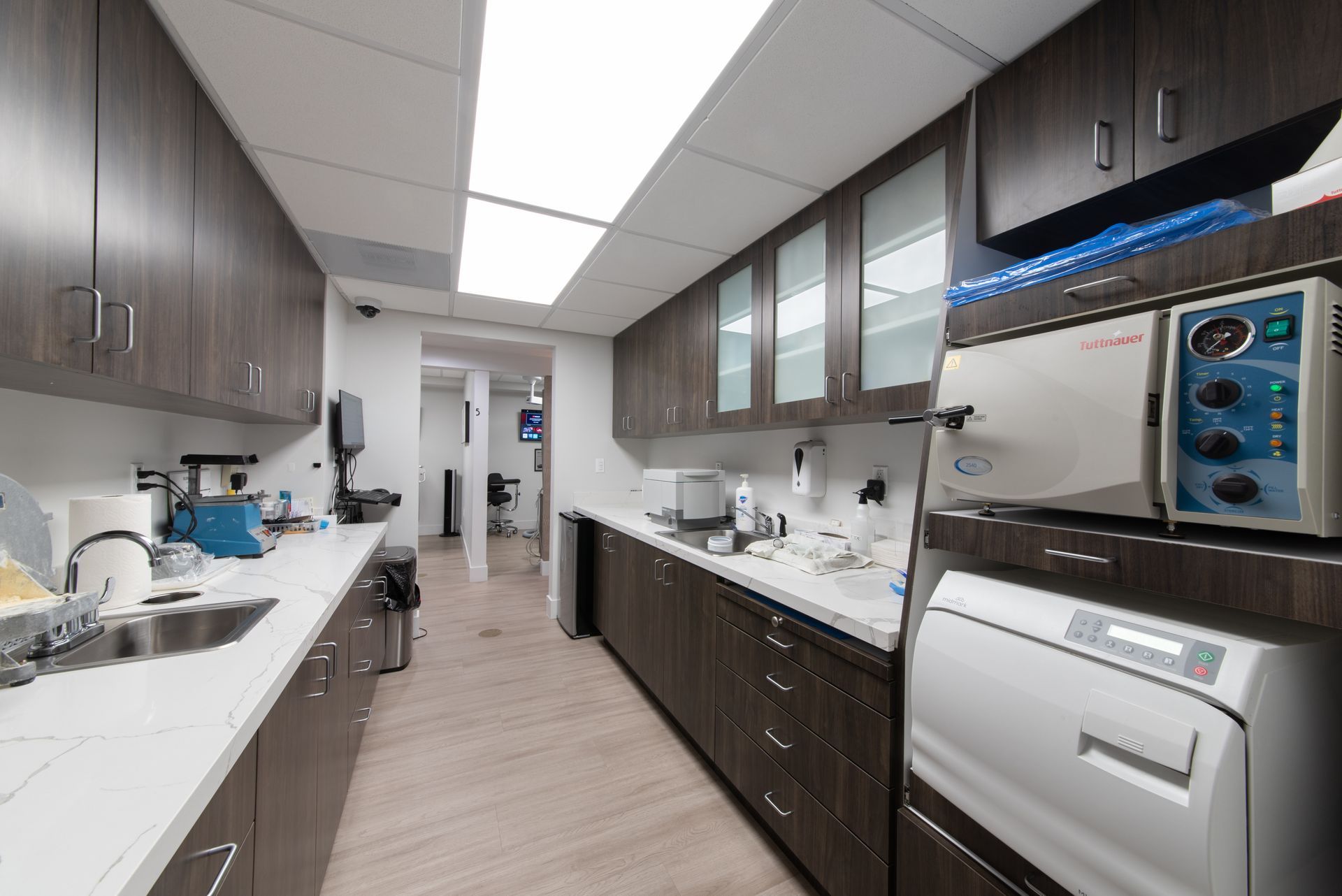 Dental office sterilization room with cabinets, sink, and equipment.