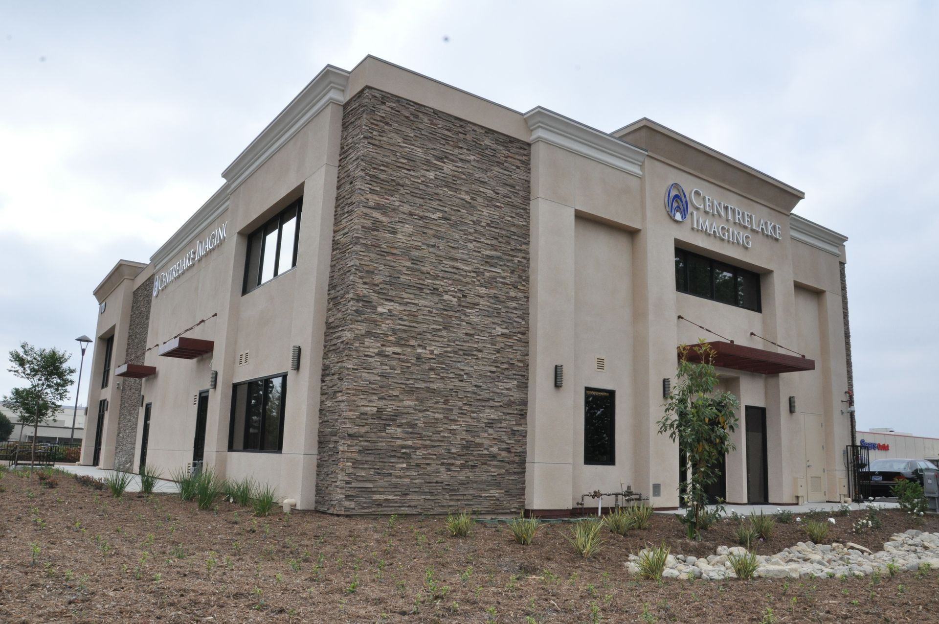 Two-story beige building with stone facade and sign for 