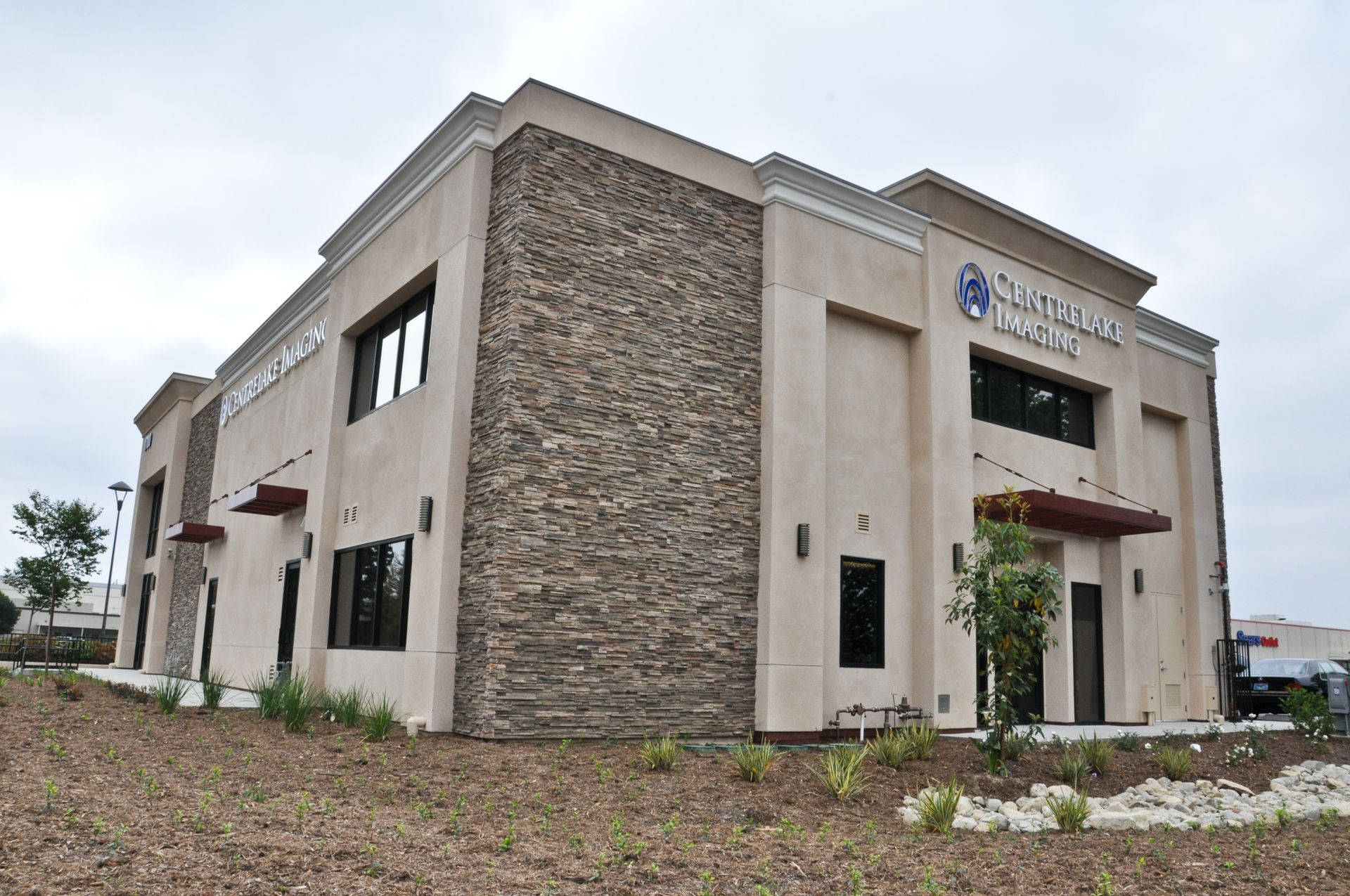 Two-story beige building with stone accent, sign for 