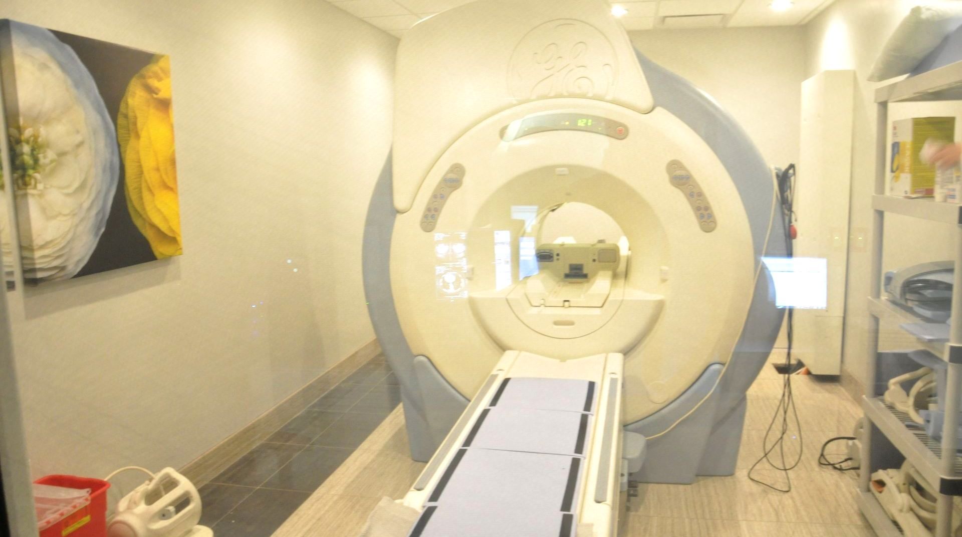 MRI machine in a medical exam room. Light blue and white colors. A stretcher extends into the opening.