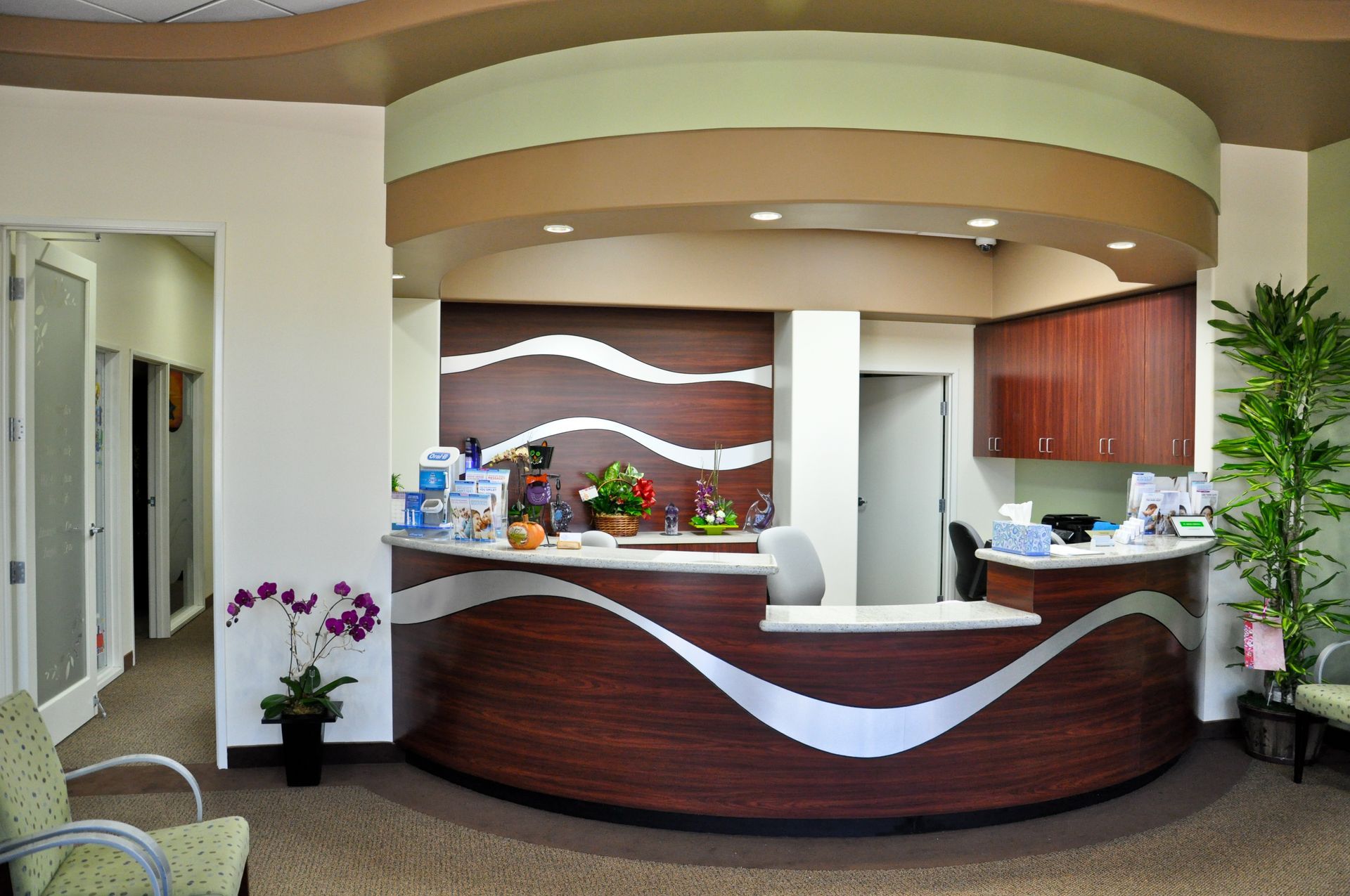 Reception area with curved wooden desk and floral arrangements.