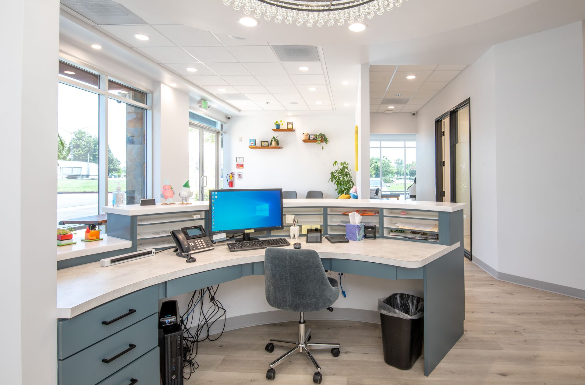 Reception desk in a dental office with a computer, chair, and trash can. Blue and white decor.