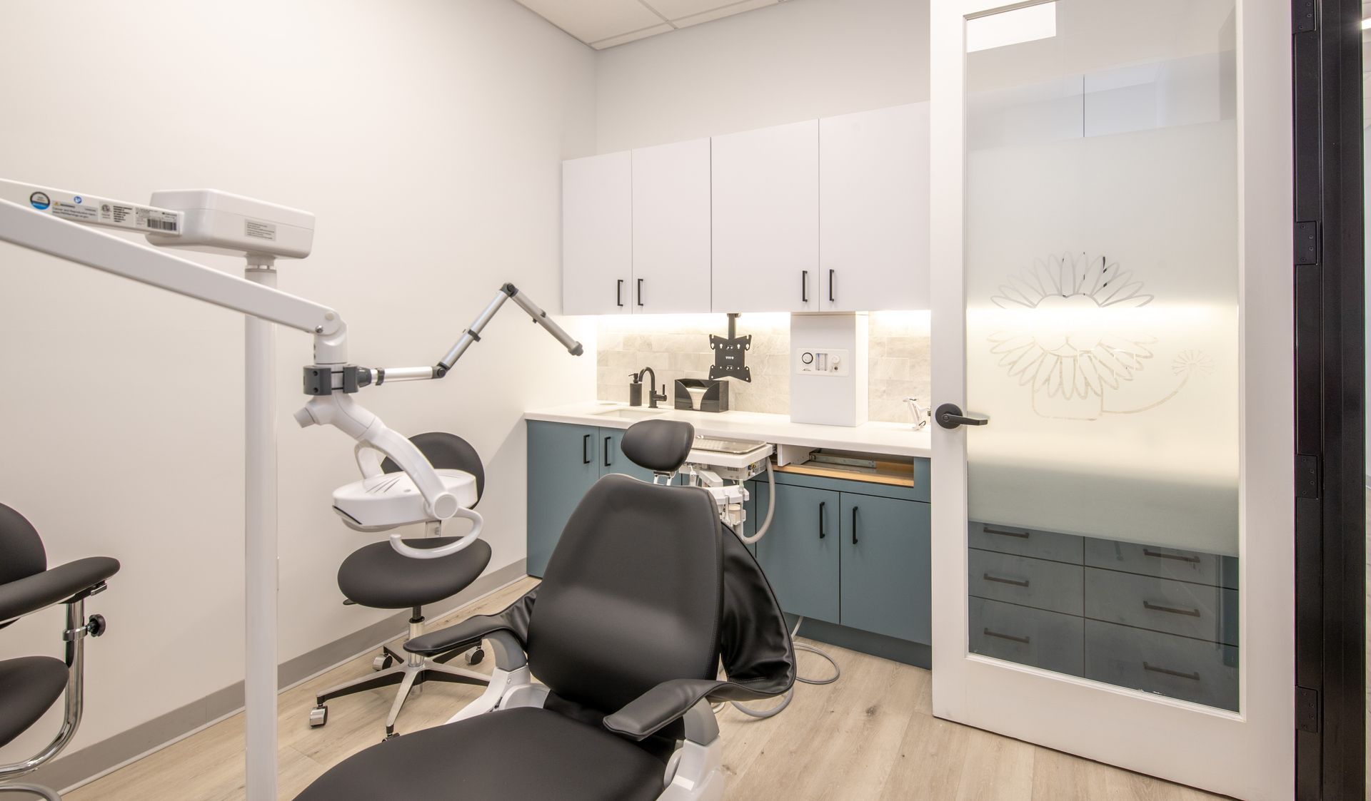 Dental office exam room with chair, cabinets, and dental equipment.