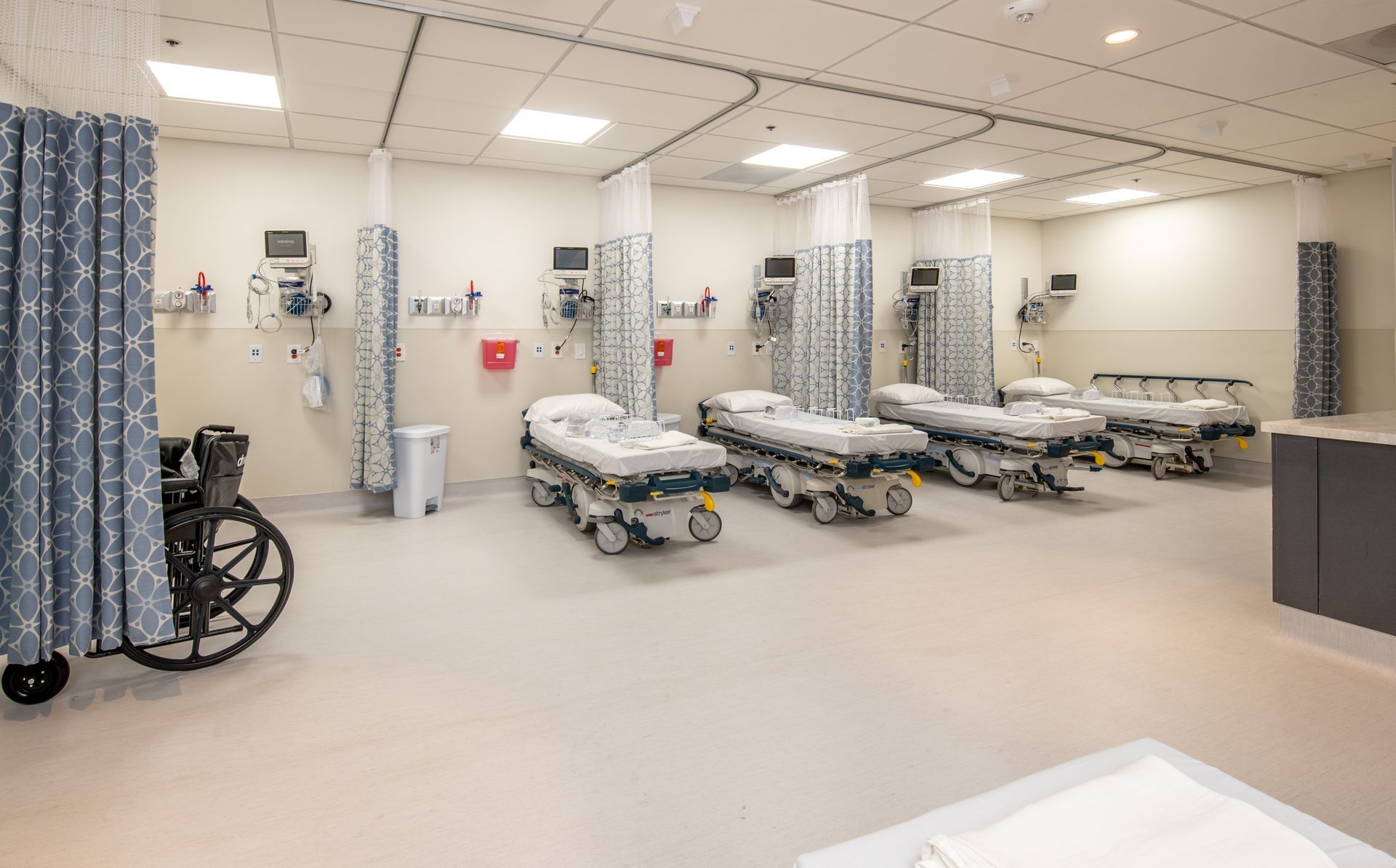 Emergency room with stretchers, medical equipment, and privacy curtains.