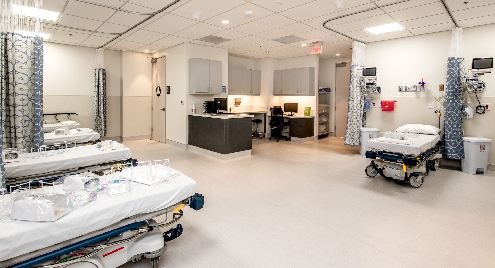 Bright, sterile hospital room with patient beds, medical equipment, and nurses' station.