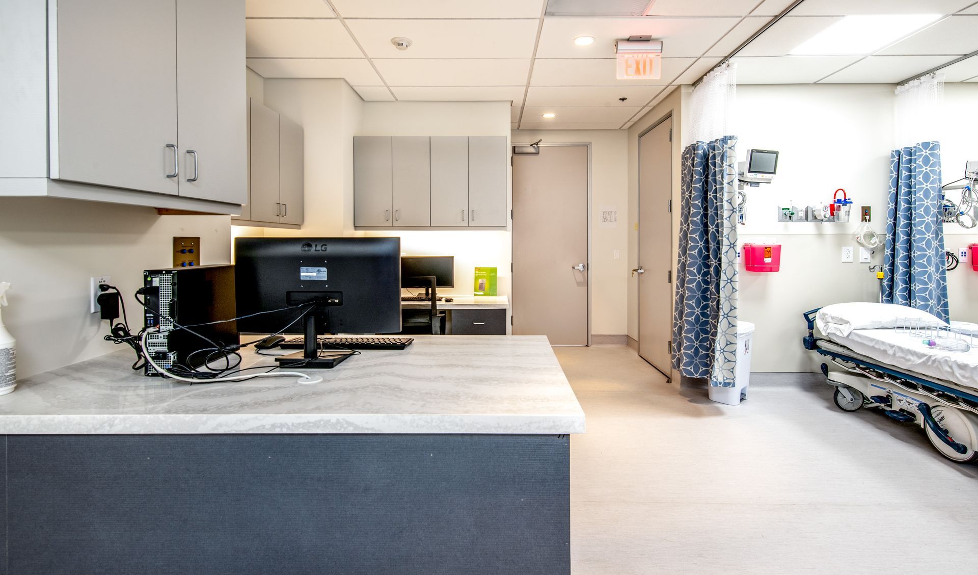 Medical office with a desk, computer, and hospital bed.