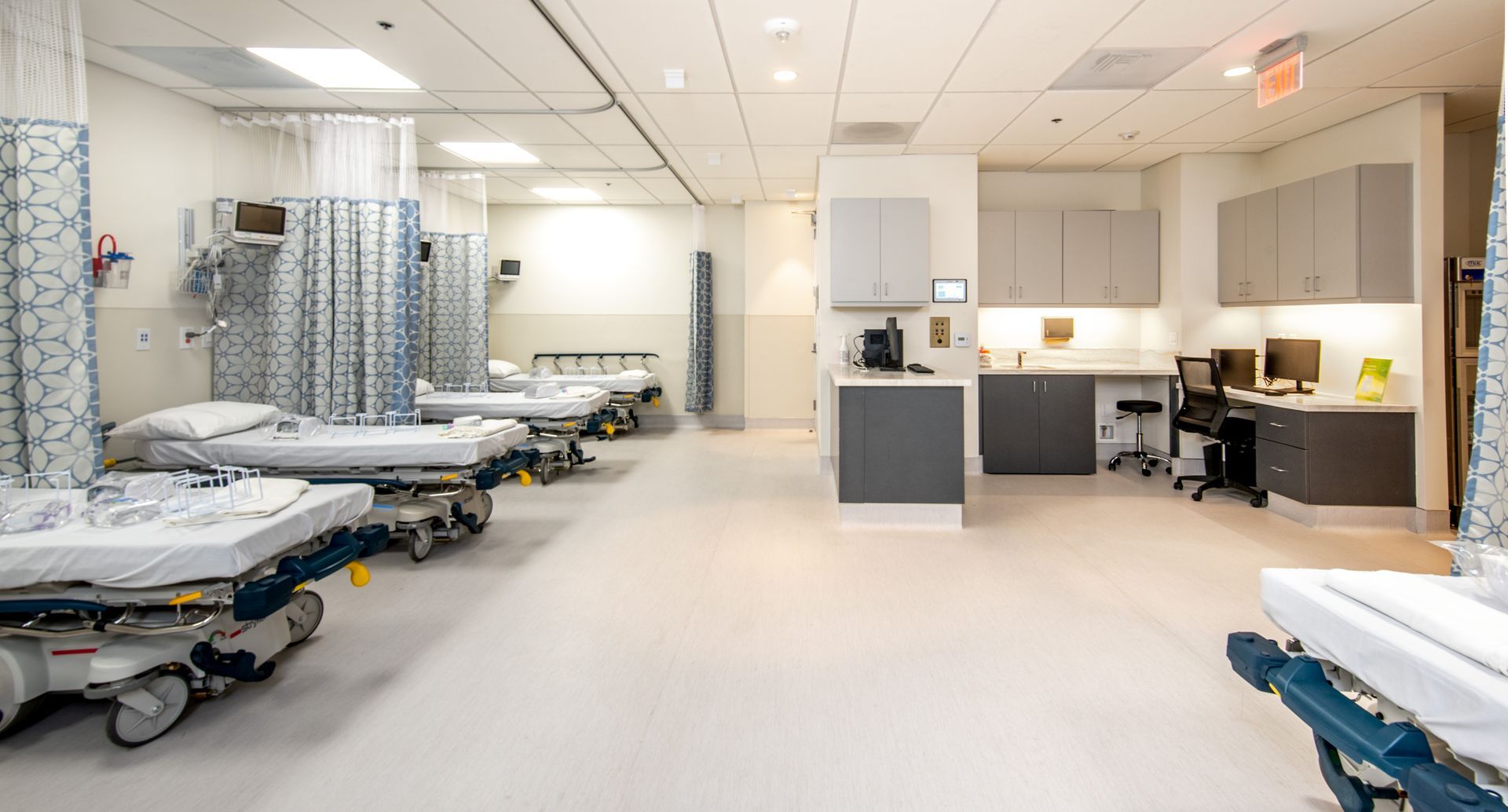 Emergency room with several beds and equipment, white walls and flooring.