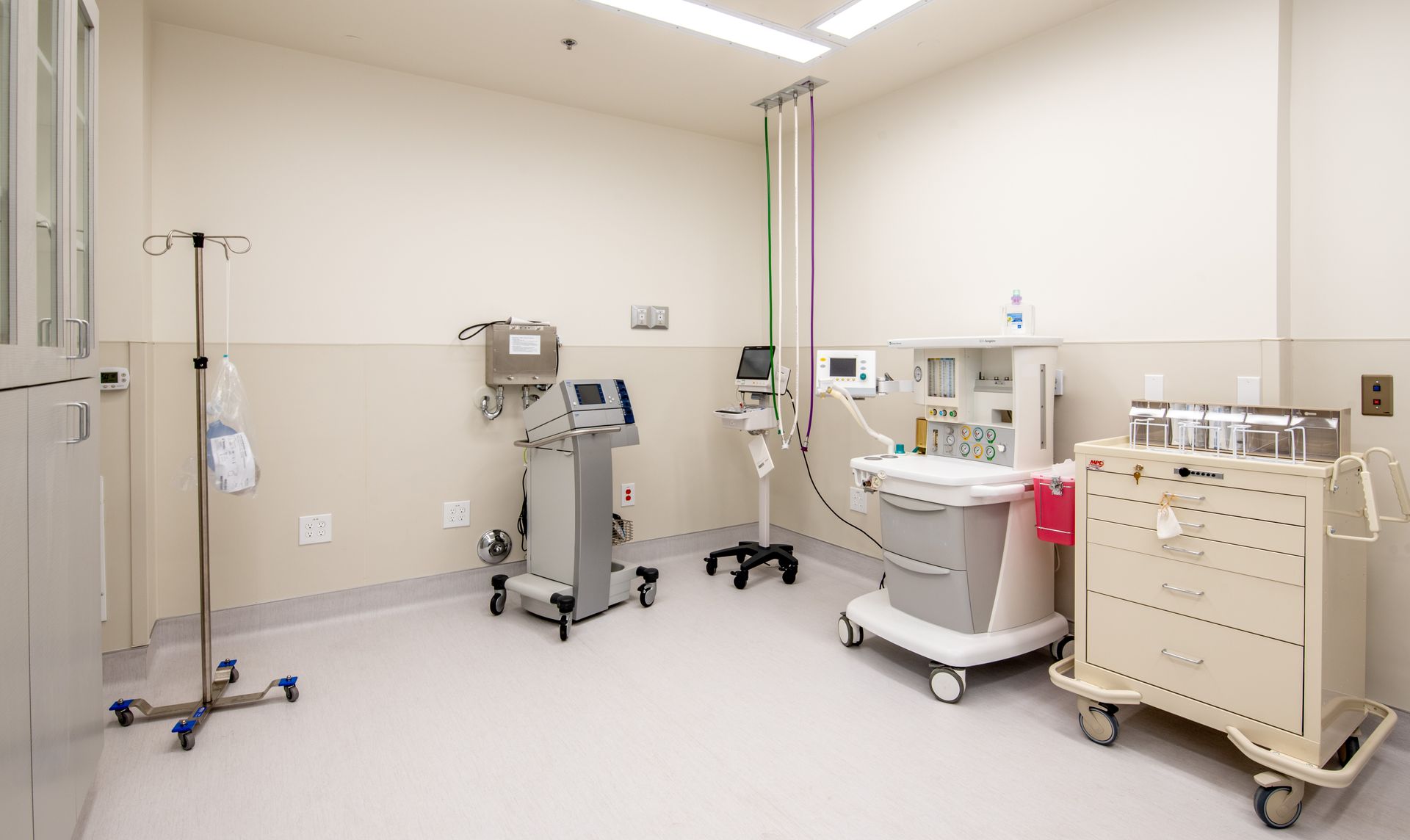 Medical equipment in a sterile room: a ventilator, cart with supplies, IV stand.