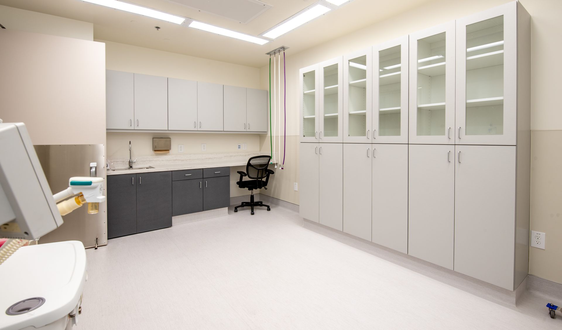 Medical exam room with white cabinets, sink, and medical chair.