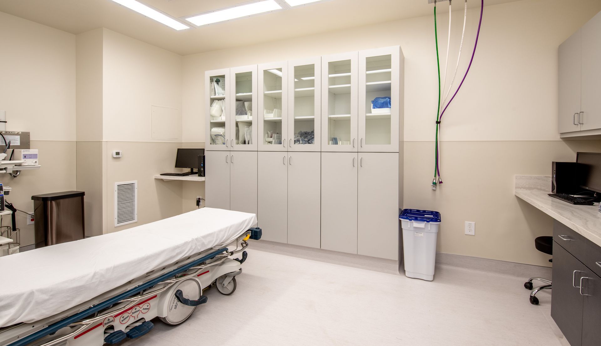Medical room with a bed, cabinets, and medical equipment.