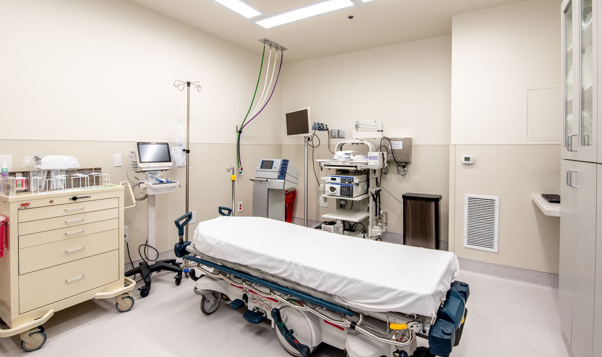 Hospital emergency room with a bed, medical equipment, and a rolling cart.