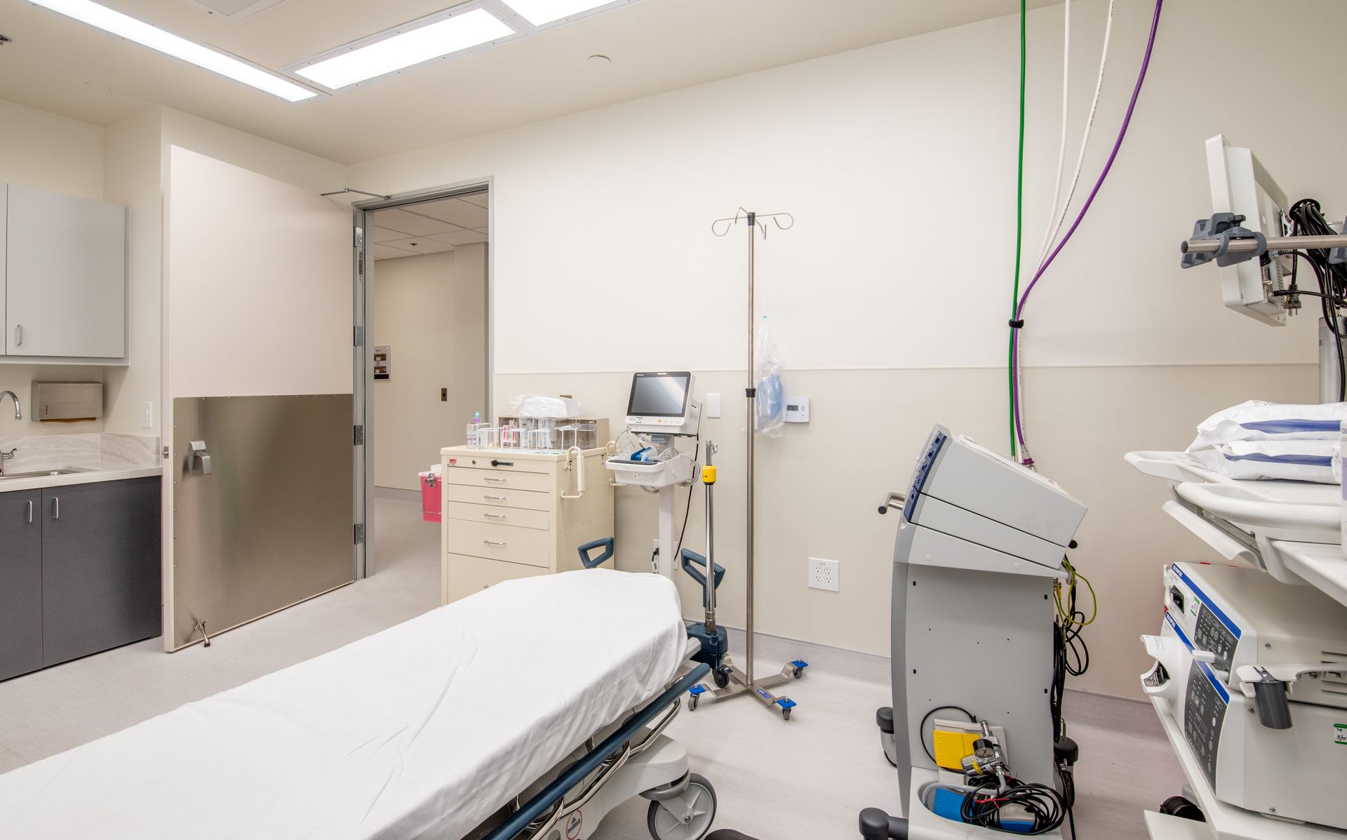 Medical room with a bed, equipment, and open doorway.