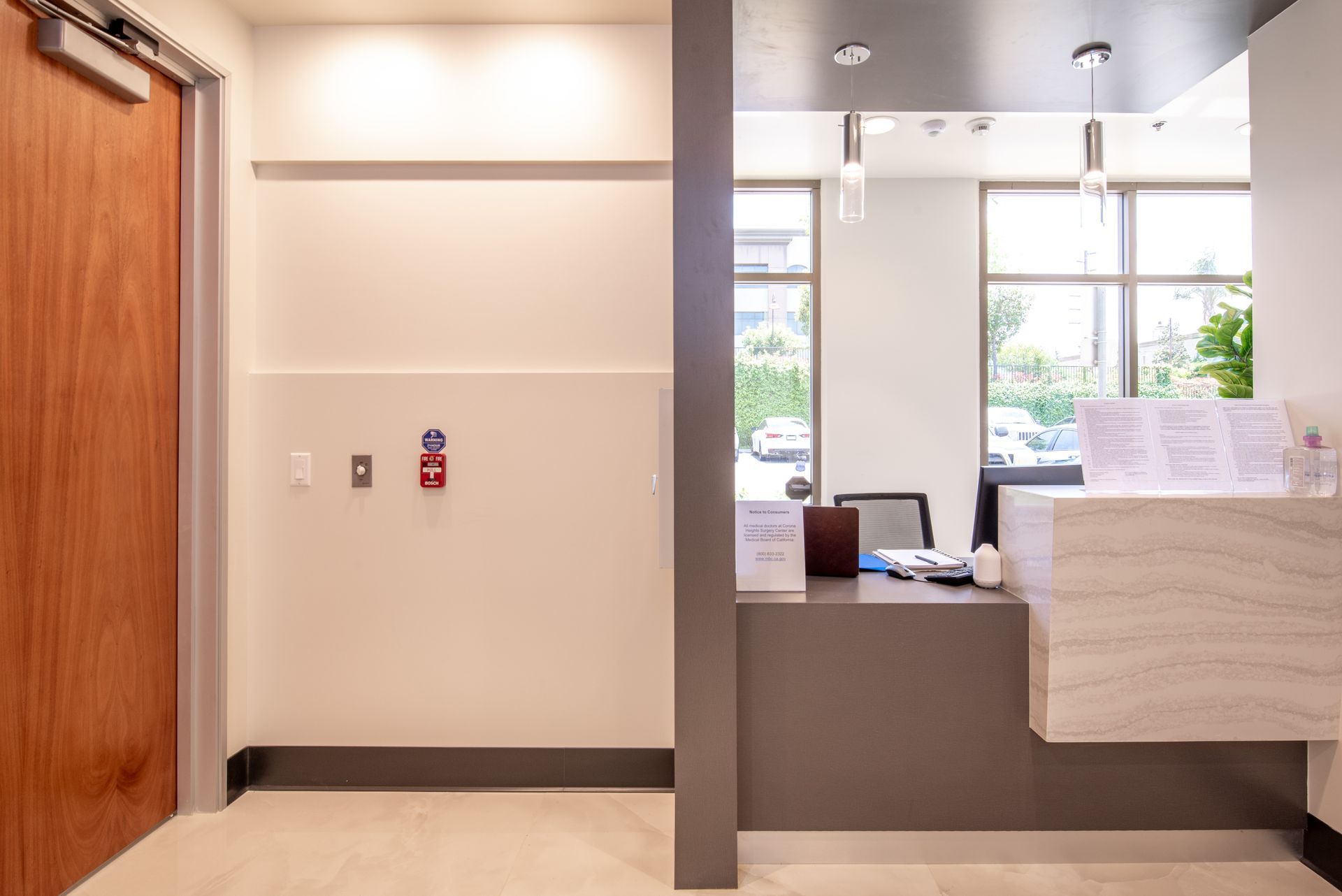 Reception area with white walls, wooden door, and a modern gray and white front desk.