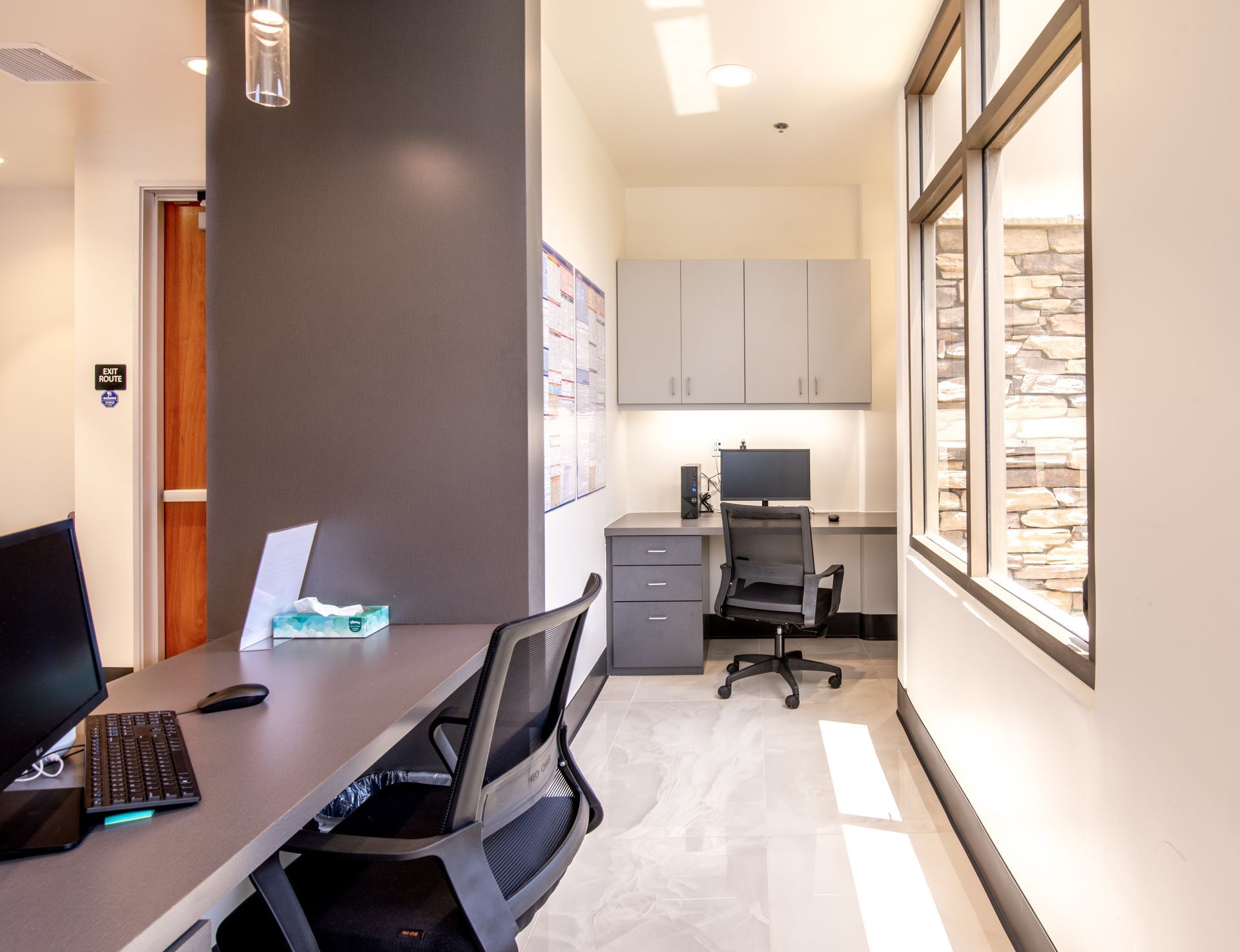 Office hallway with a desk, computer, and a workspace near a window.