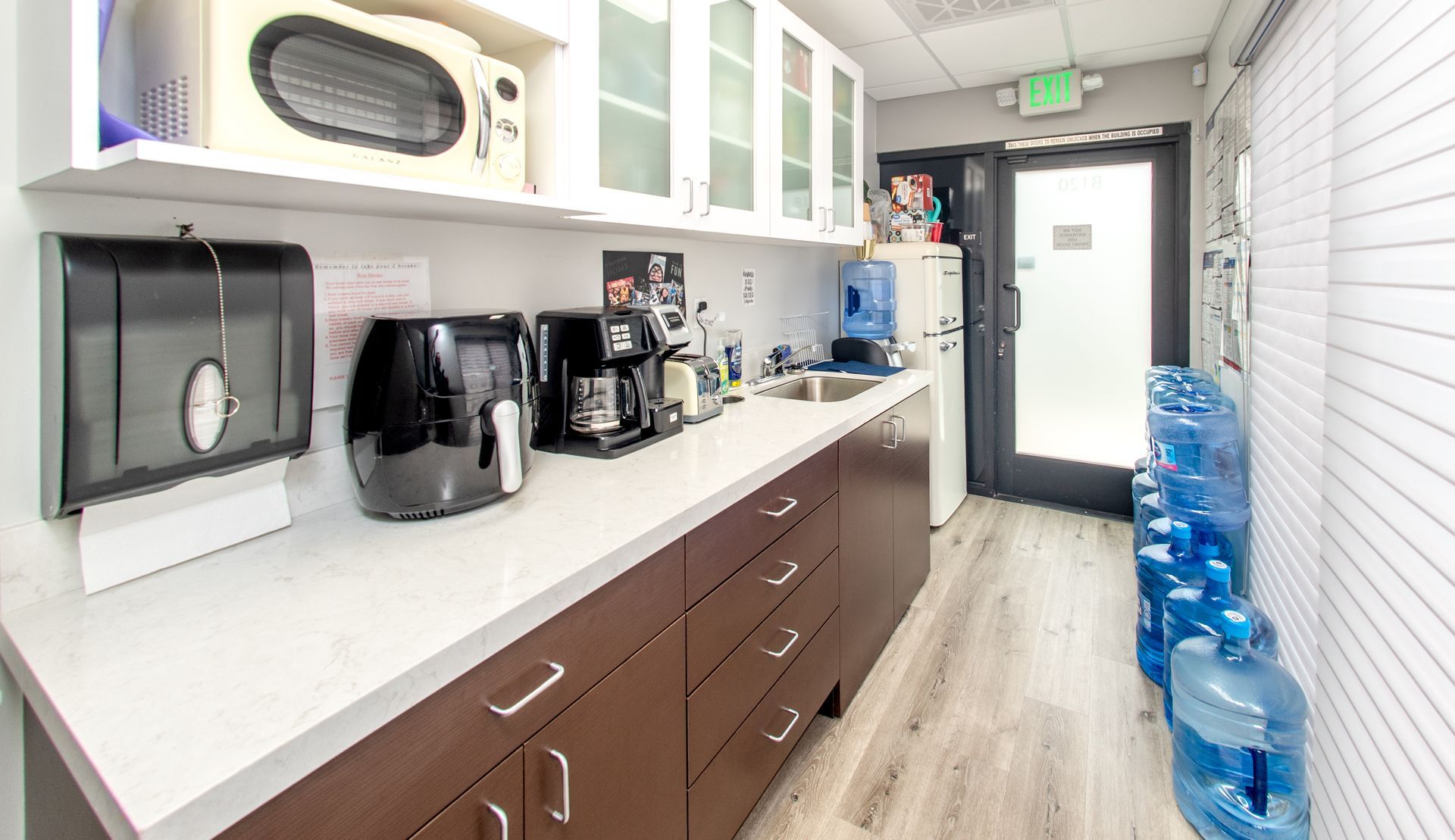 Office kitchen with microwave, coffee maker, and water cooler.
