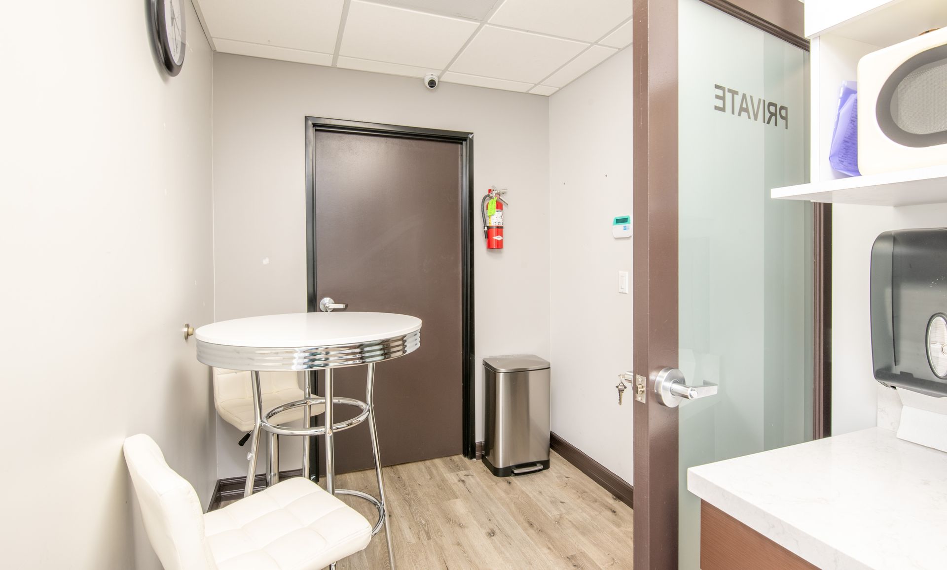 A small, modern office space with a round table, chair, and a door labeled 