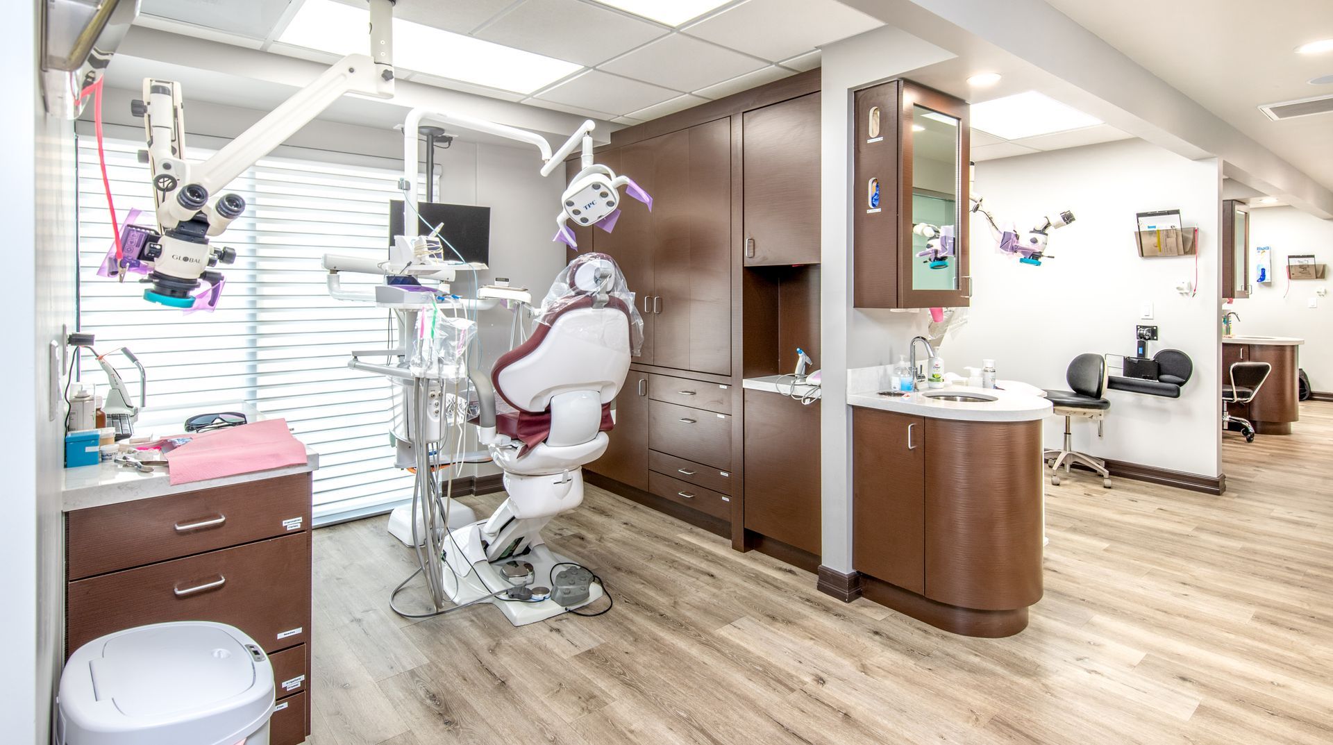 Dental office examination room, dental chair, tools, cabinets, bright.