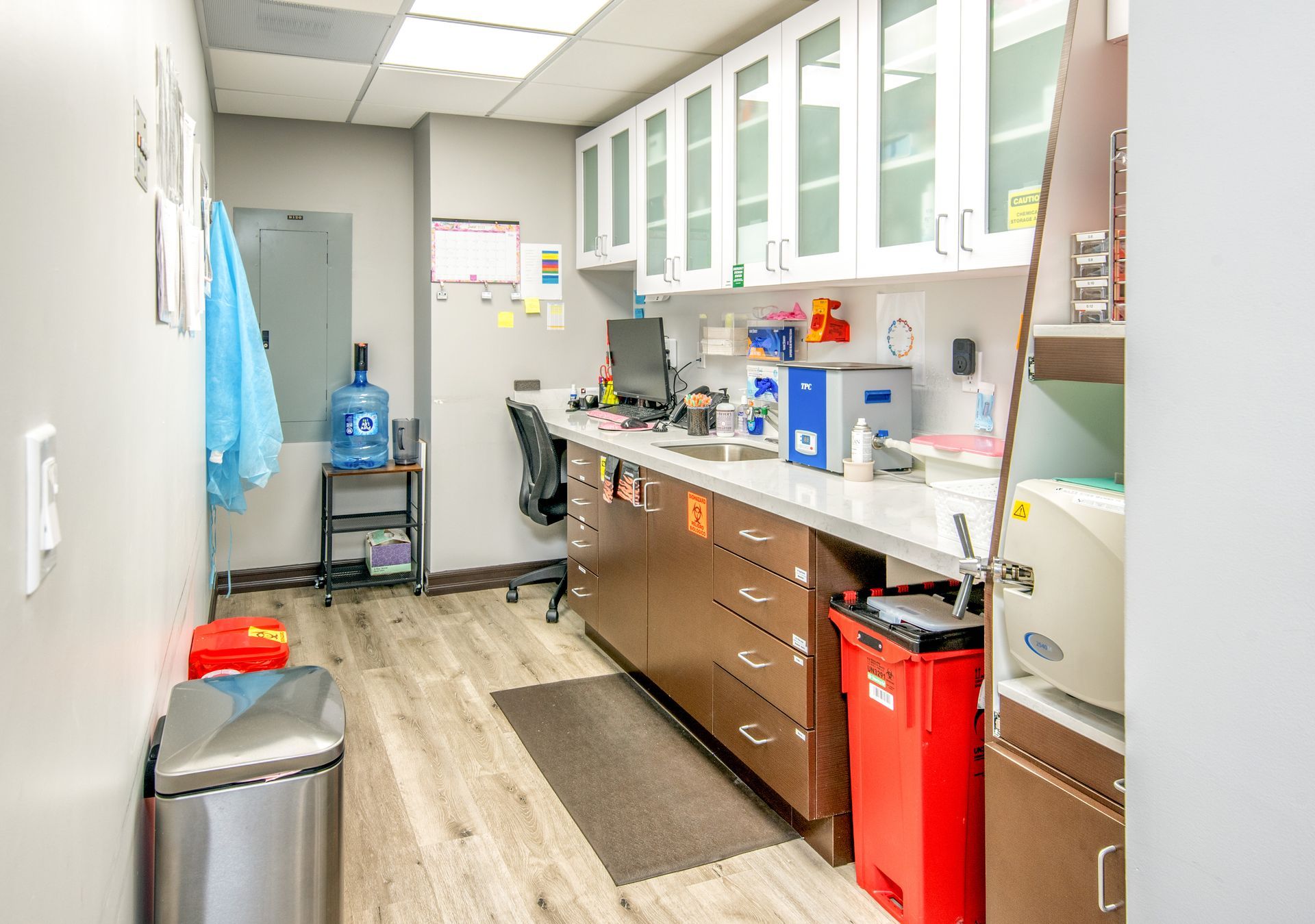 Laboratory with white cabinets, brown counter, and stainless steel trash can.