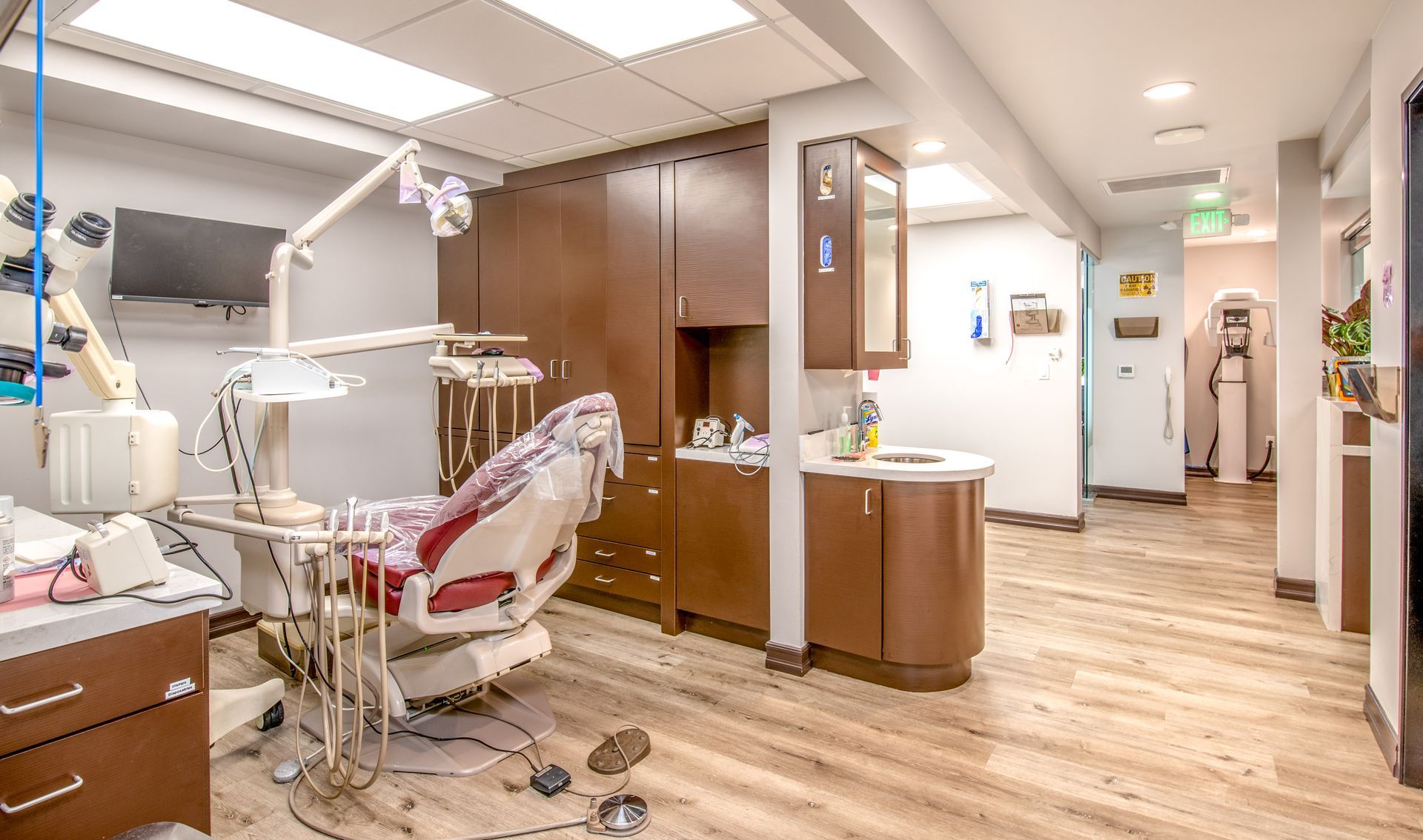 Dental office with a chair, tools, cabinets, and a hallway.