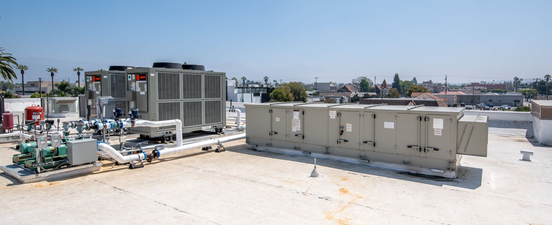 Rooftop HVAC equipment on a white roof with a clear blue sky.