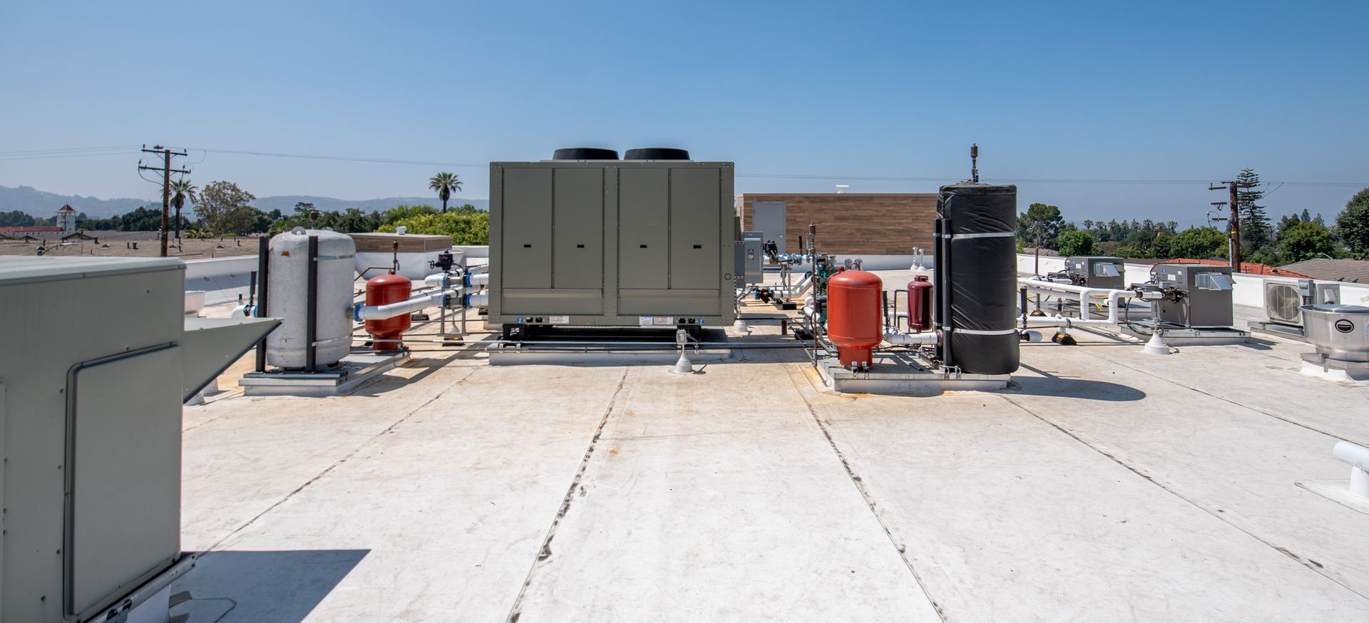 View of a rooftop with HVAC equipment against a bright blue sky.