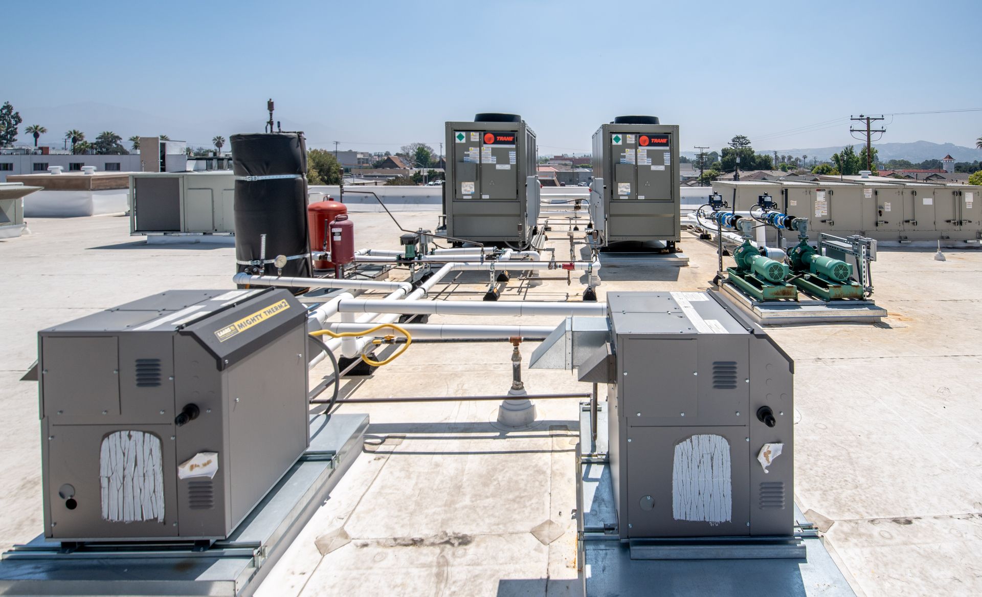 Rooftop HVAC units and related equipment on a flat roof on a sunny day.