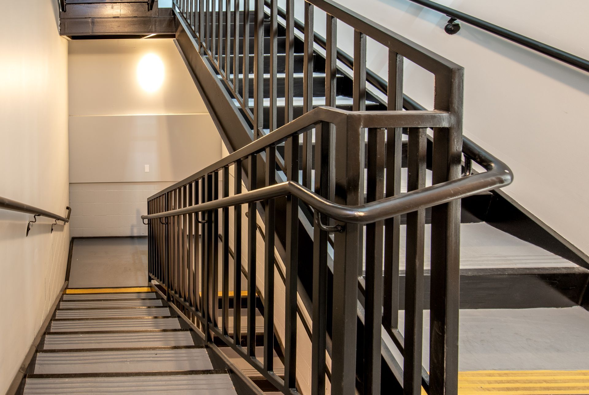 Staircase with metal railings. Dark steps and white walls.