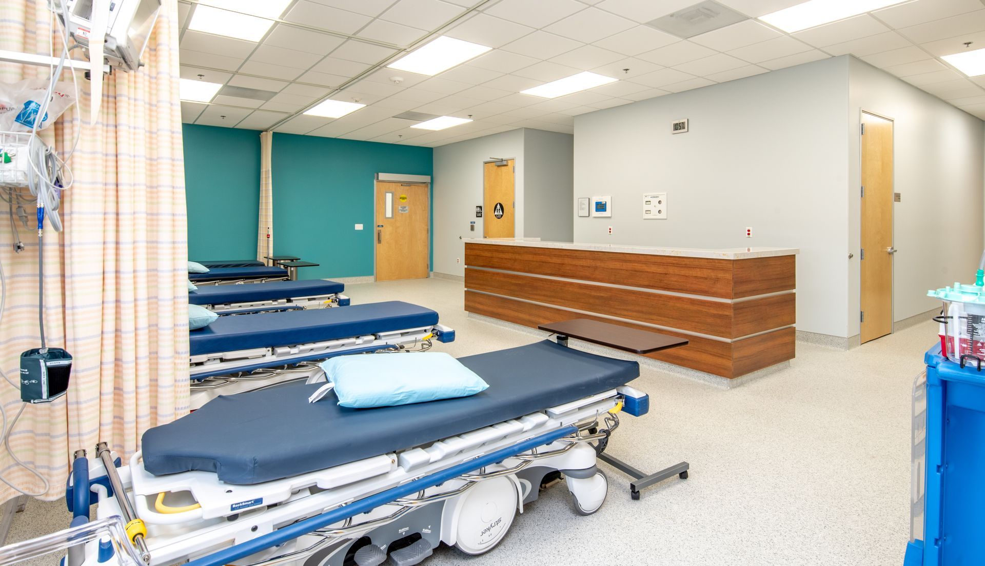 Emergency room with beds, teal wall, and reception desk.