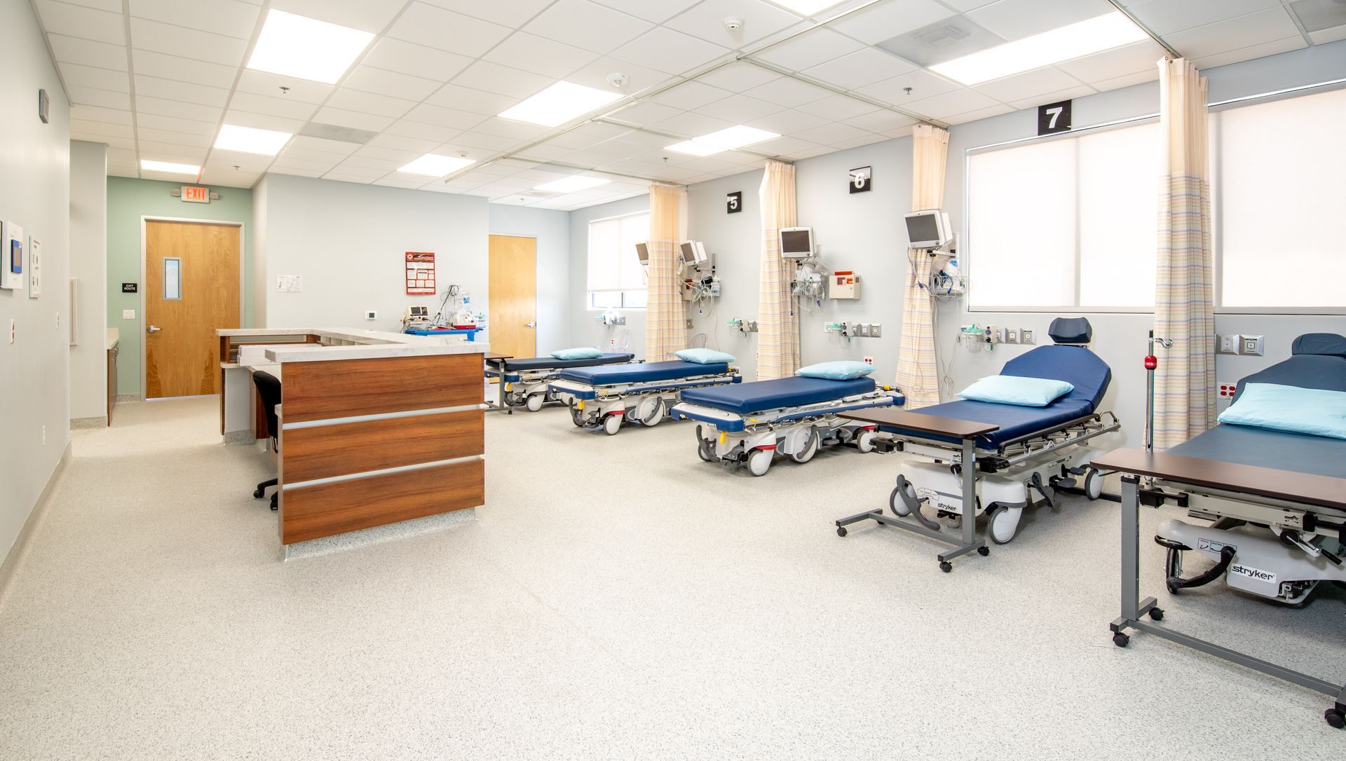 Emergency room with several beds, medical equipment, and nurses station.