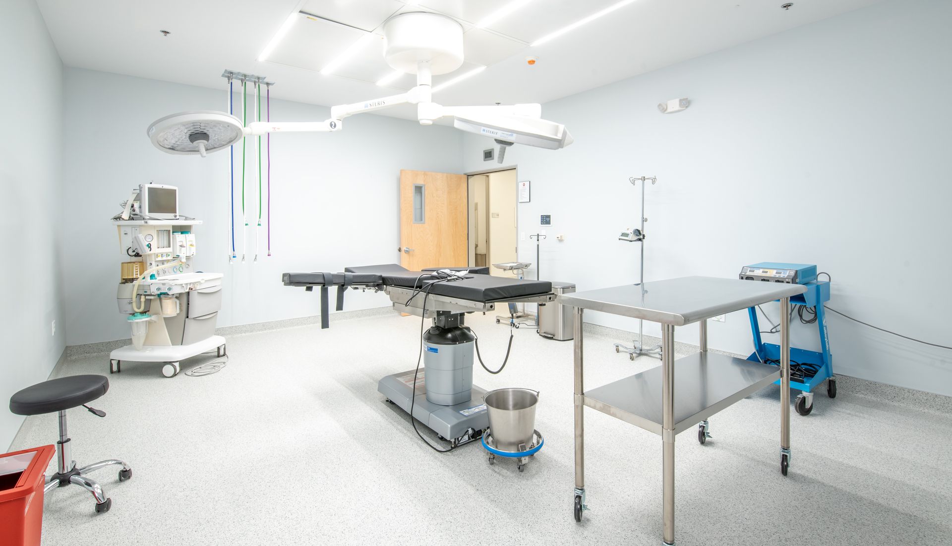 Surgical room with operating table, medical equipment, and overhead lights; setting is sterile.
