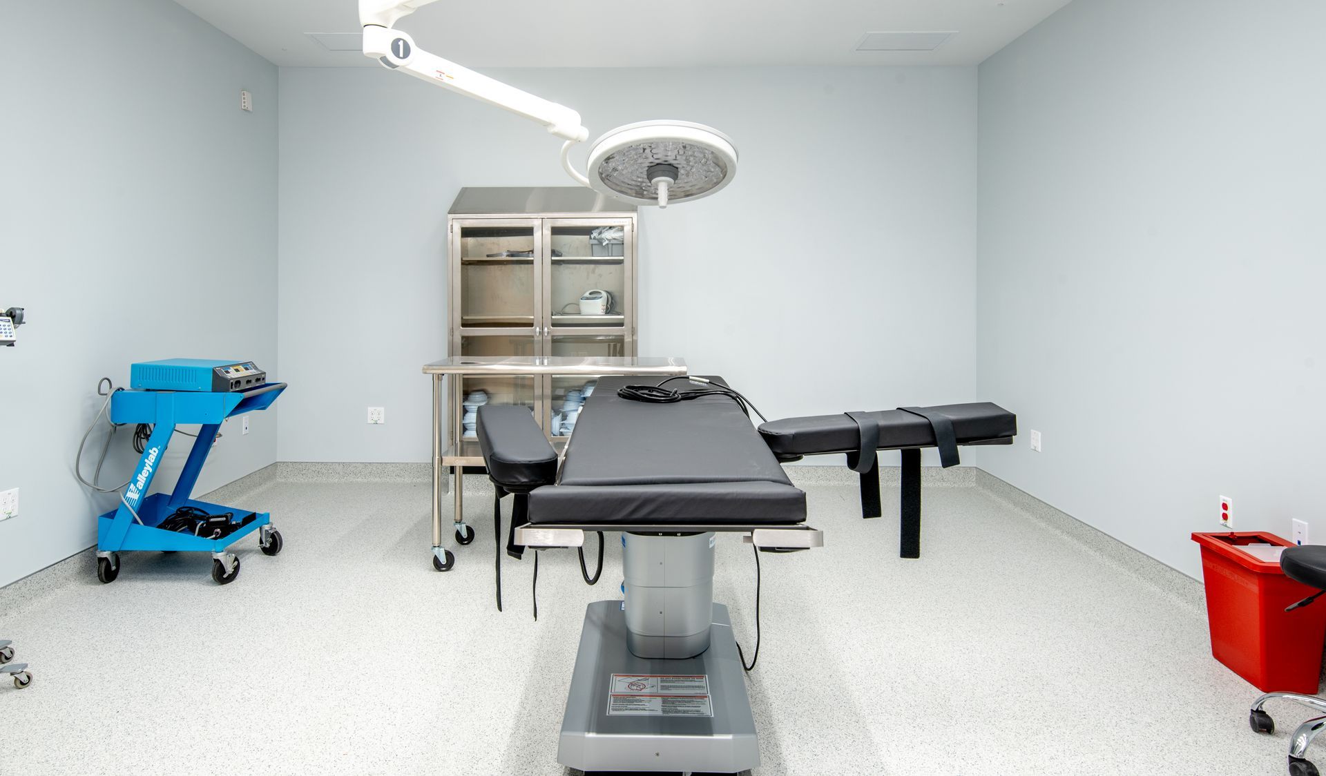 Operating room with surgical bed, equipment, and overhead light.
