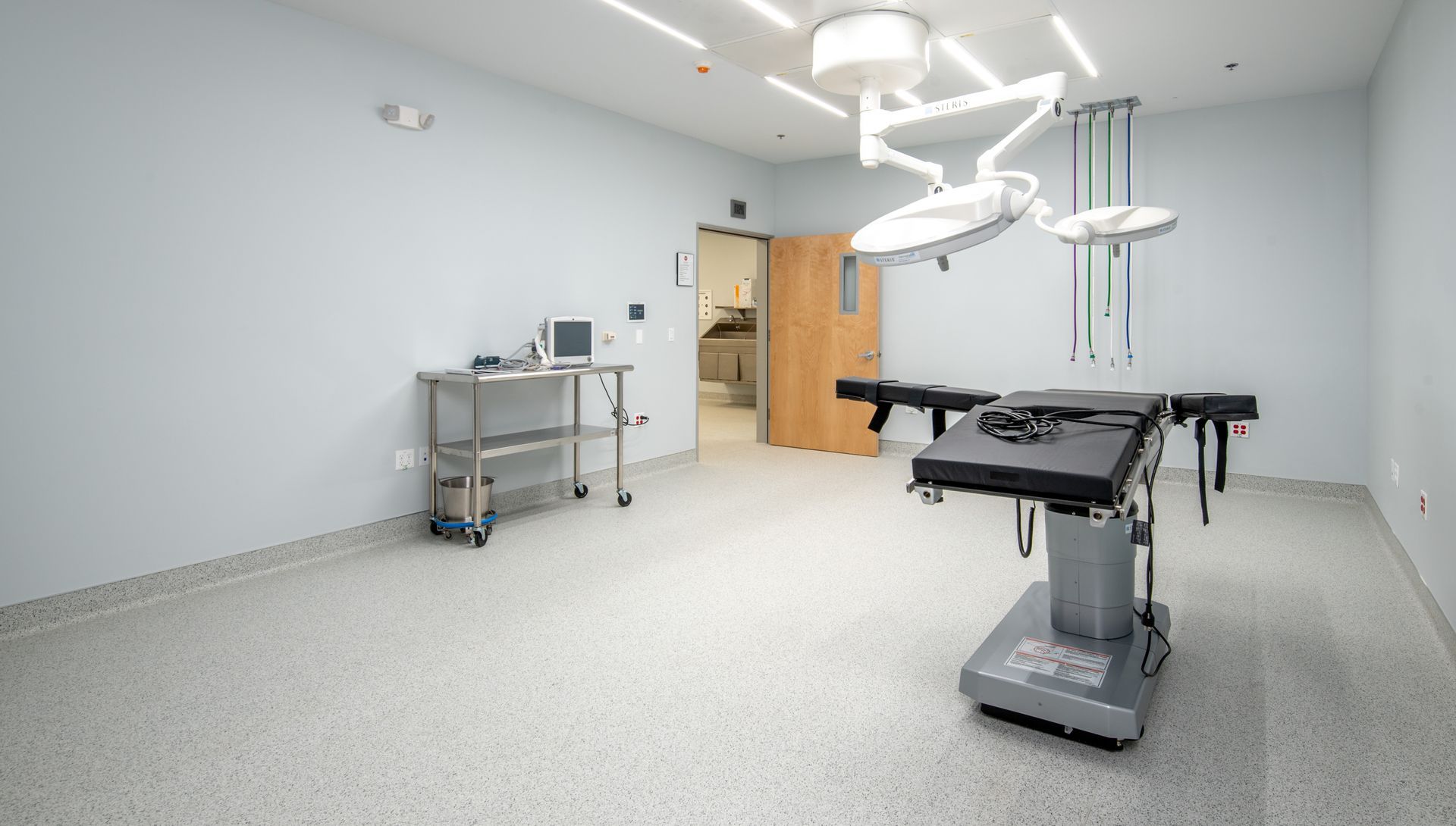Operating room with surgical table, overhead lights, and medical equipment.