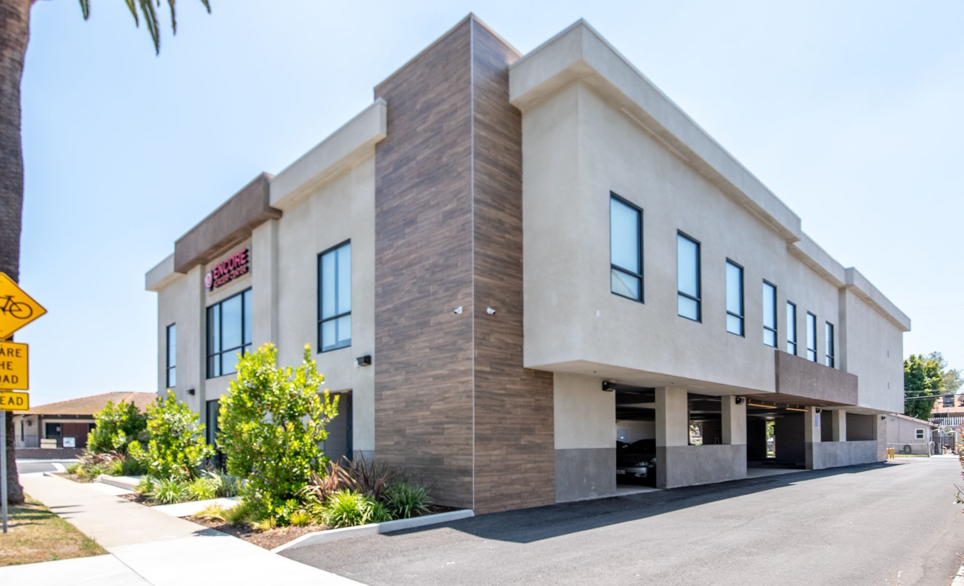 Modern two-story building with brown accent wall and recessed parking under the second floor.