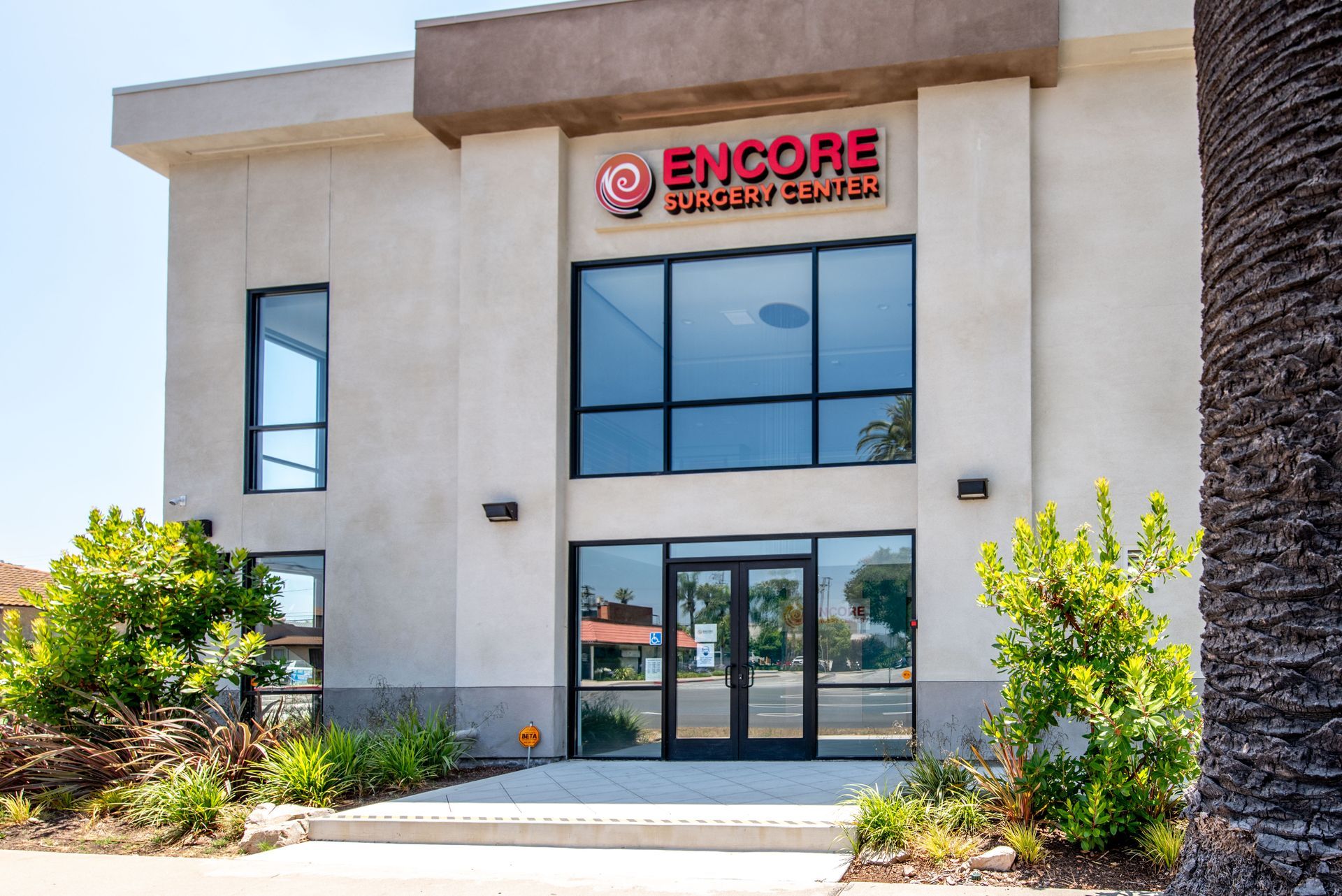 Encore Urgent Care building with glass doors and large windows. Red sign above the entrance.
