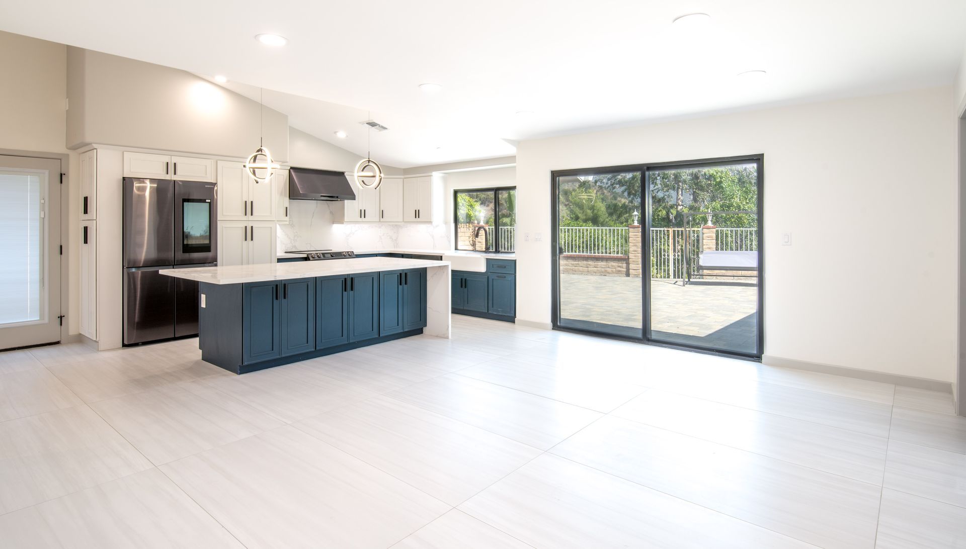Modern kitchen with blue island, stainless steel appliances, and sliding glass doors.