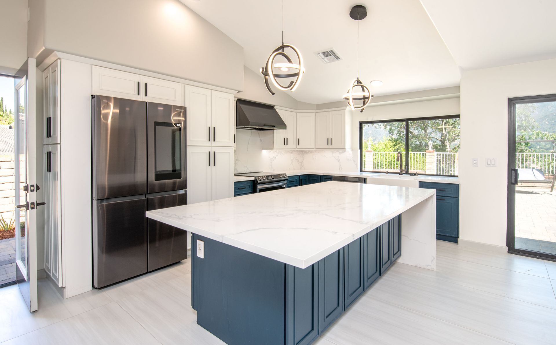 Modern kitchen with blue island, white countertops, and stainless steel appliances.