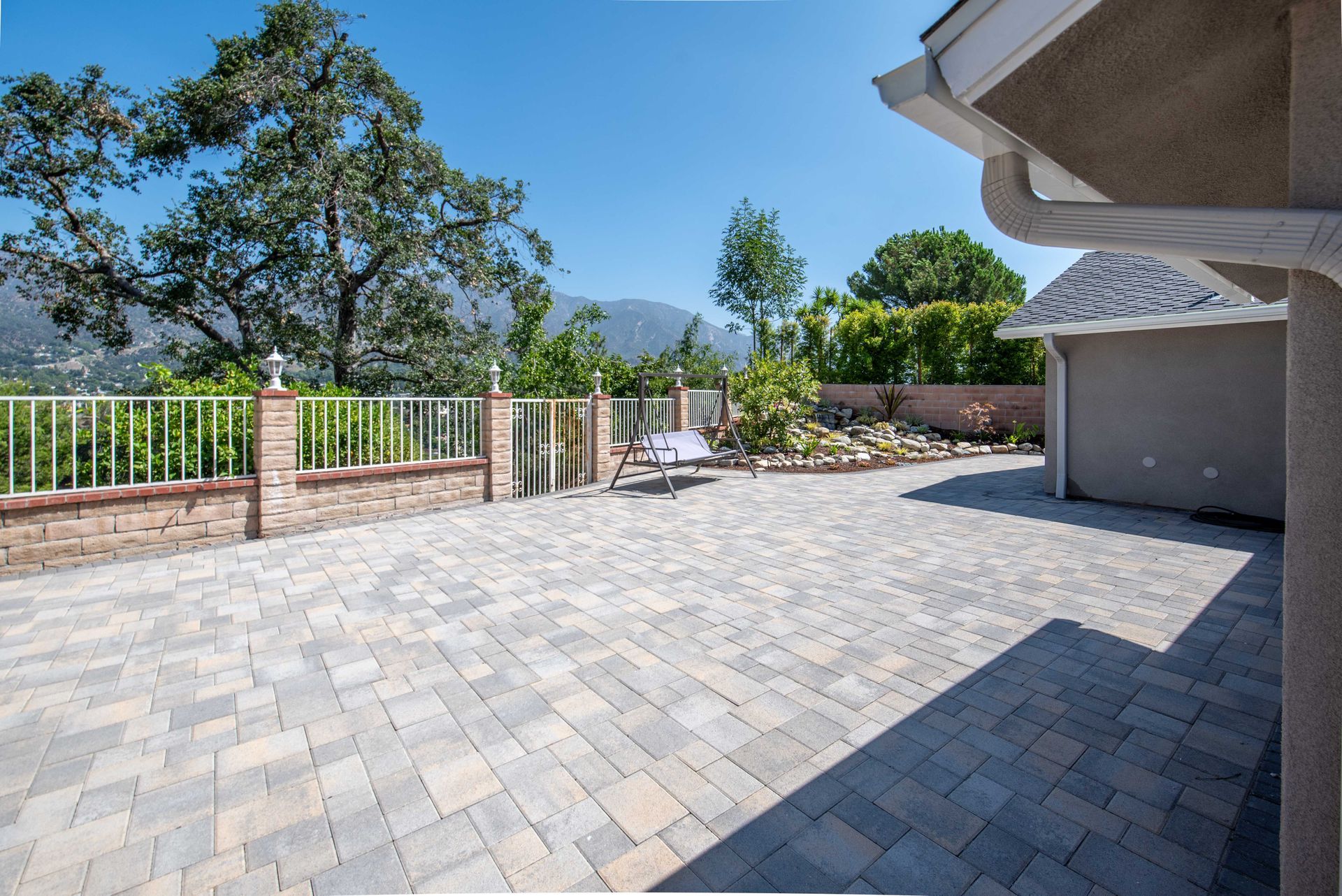 Brick patio with a white fence, overlooking mountains. Sunny day.